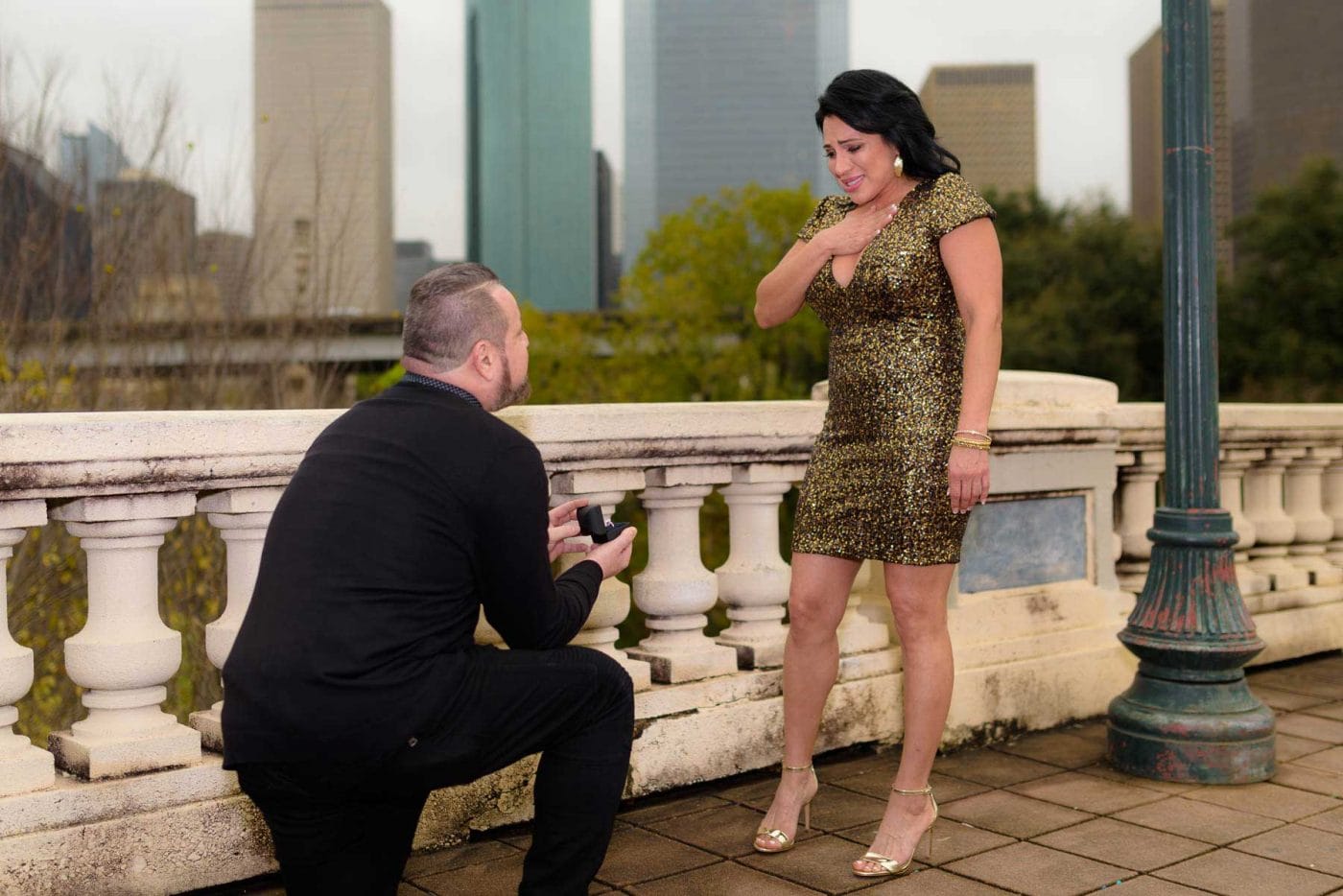 Houston Photographer: A man is romantically proposing to a woman on a beautiful bridge as the skilled photographer captures their special moment.