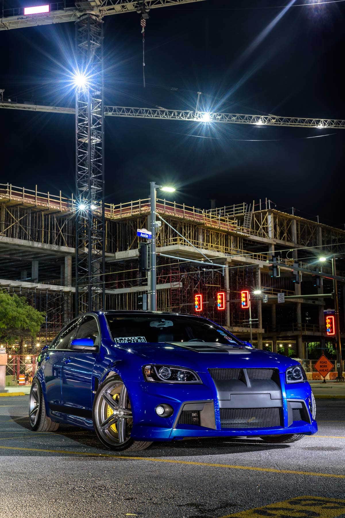 A blue car parked in front of a construction site.