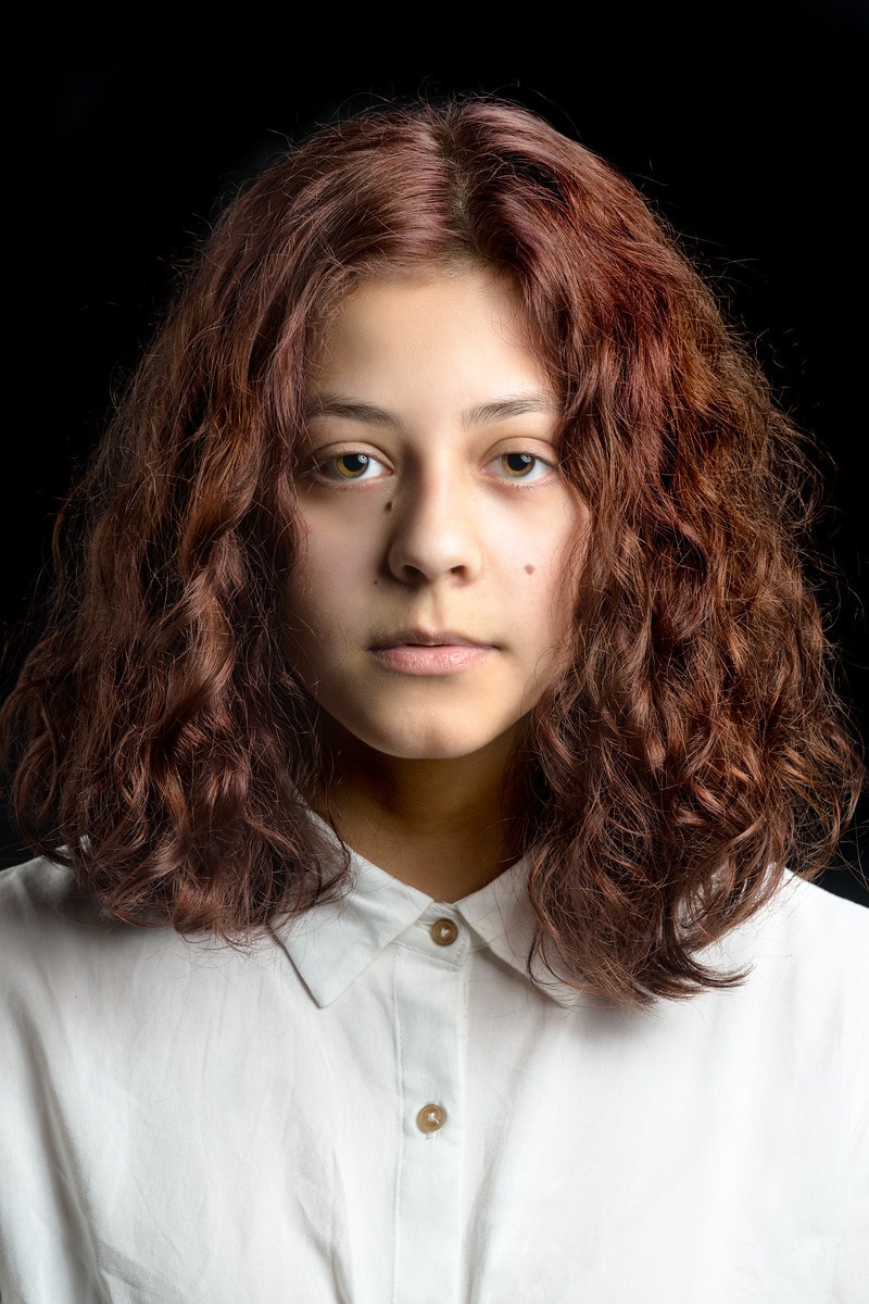 Young teenage actress model headshot, curly shoulder length hair, white button up