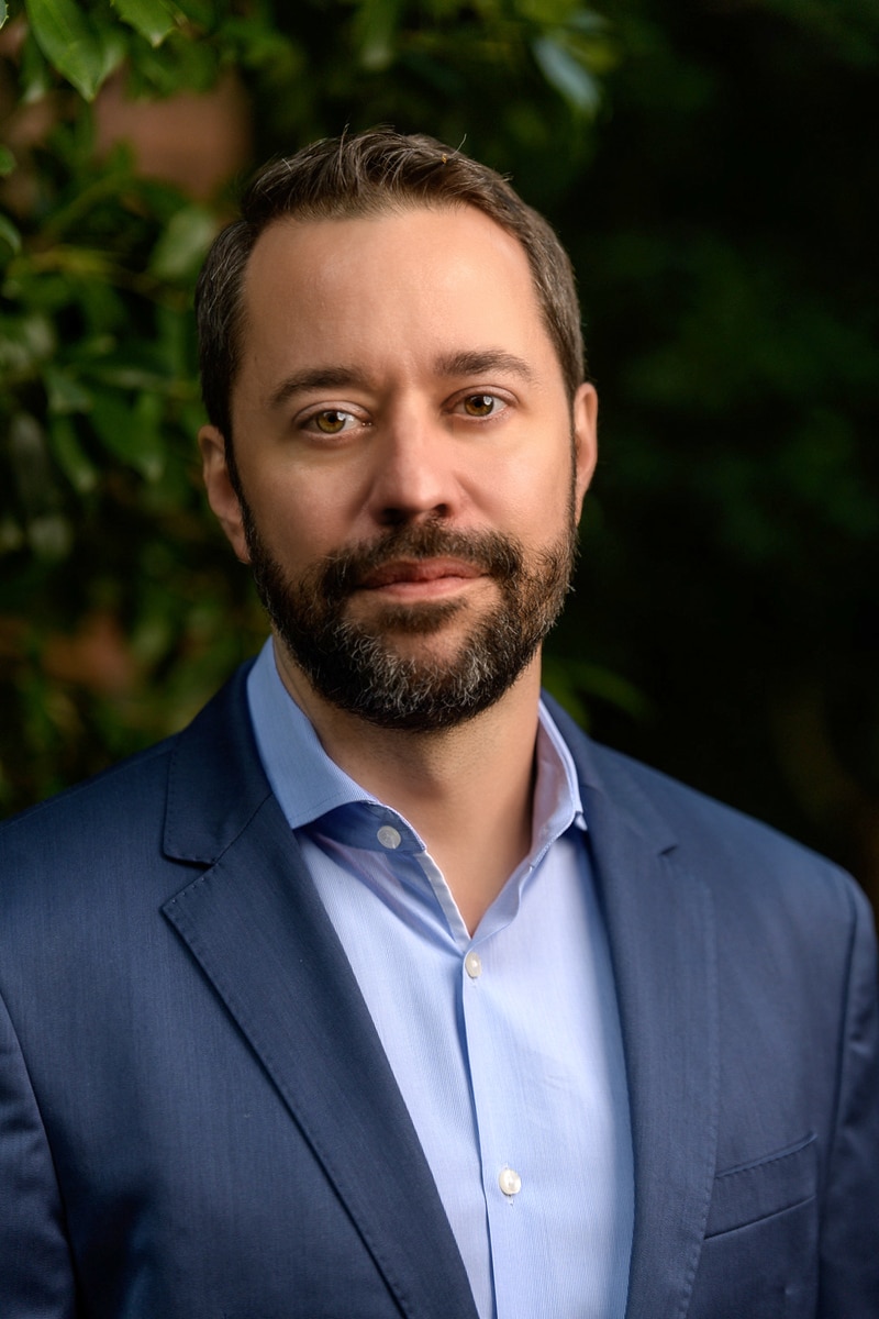 outdoor headshot, studio lighting in front of green plants, blue suit casual