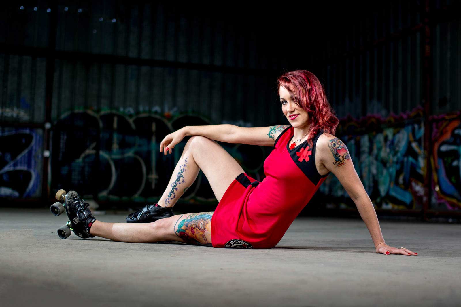 tattooed redhead roller derby posing in abandoned graffiti warehouse