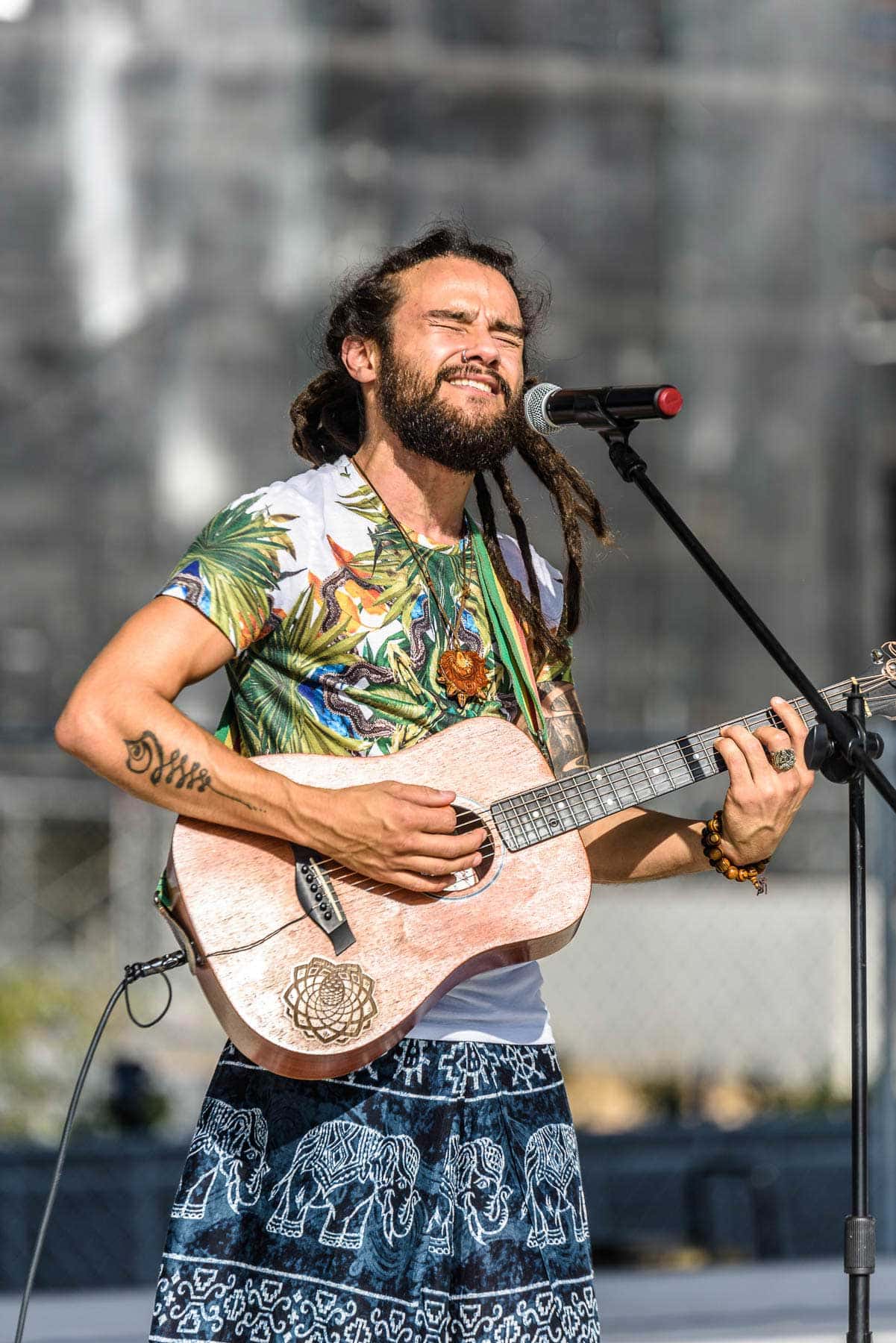 A man with dreadlocks playing an acoustic guitar.