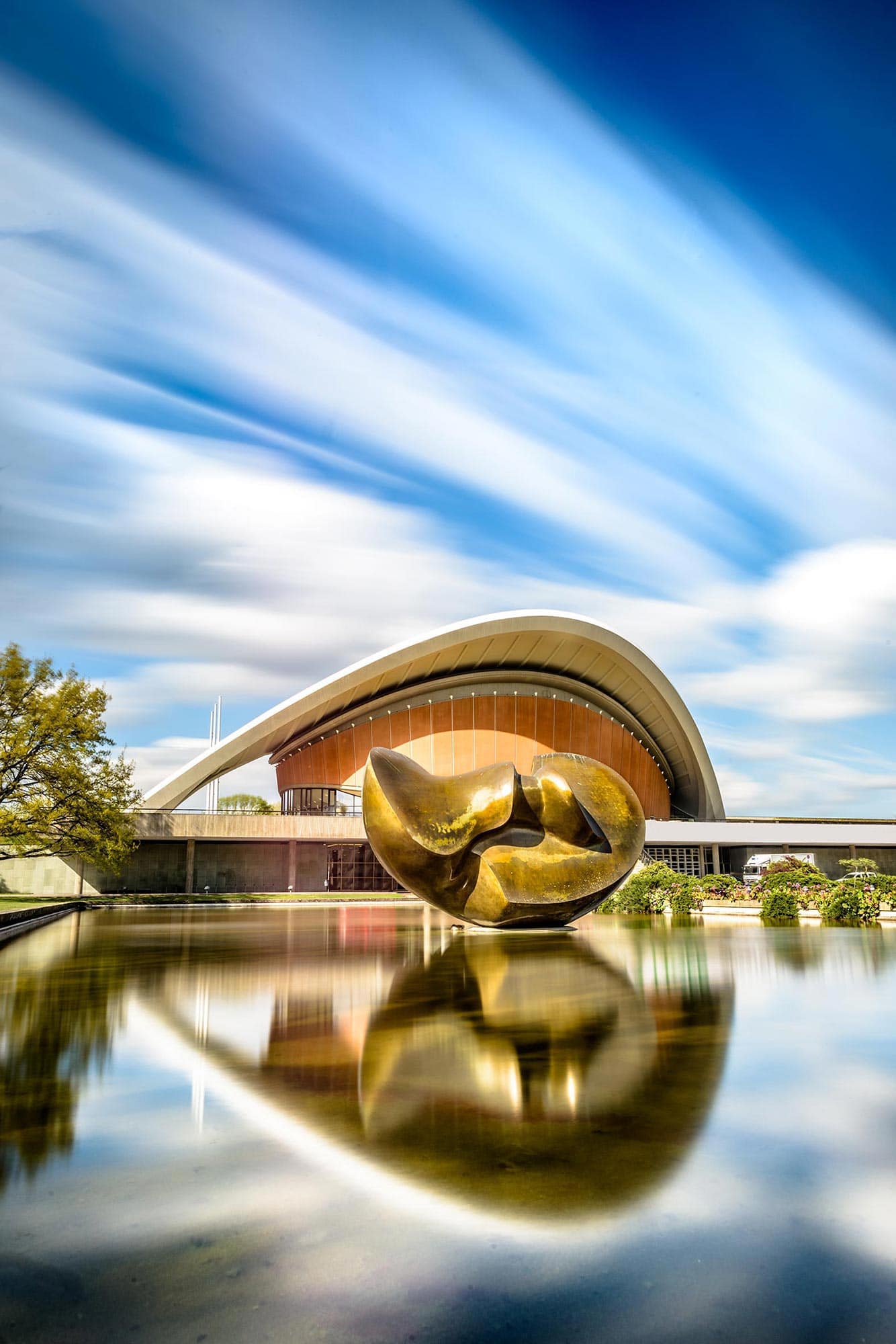 A large building with a golden sphere reflected in a body of water.