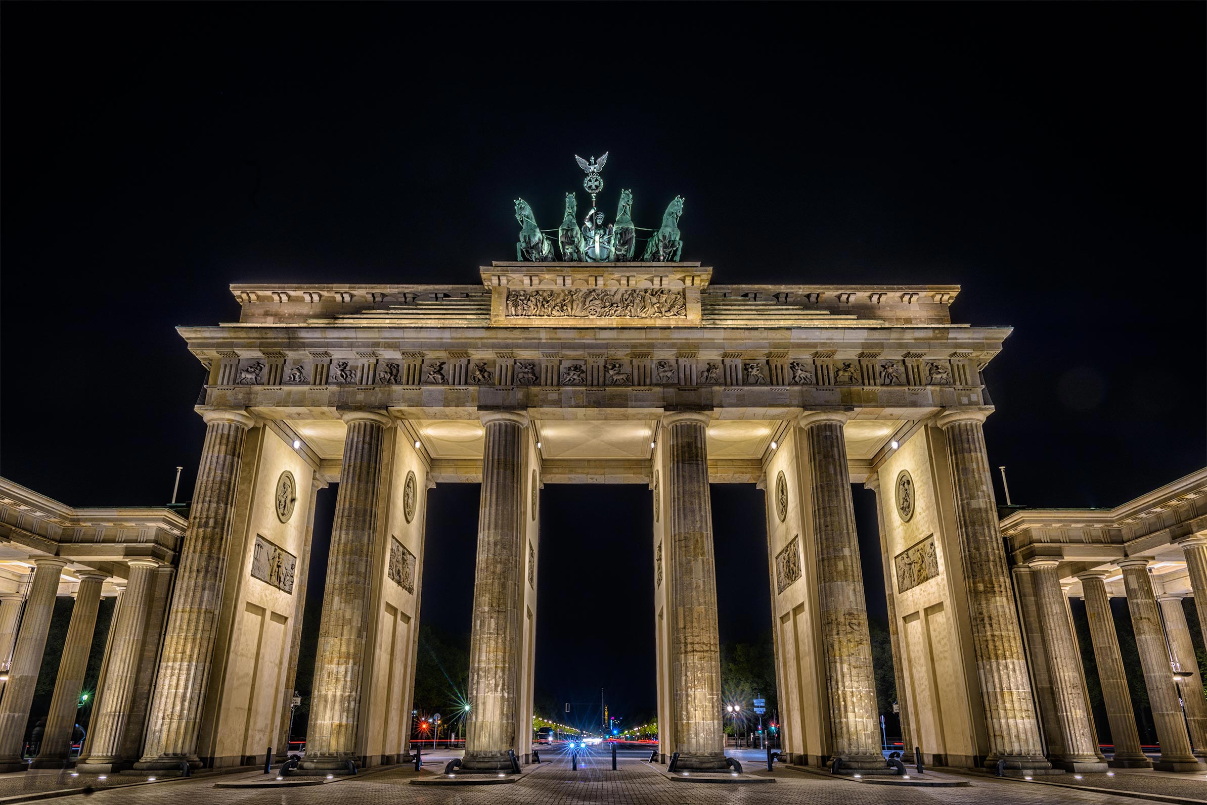 The brandenburg gate is lit up at night.