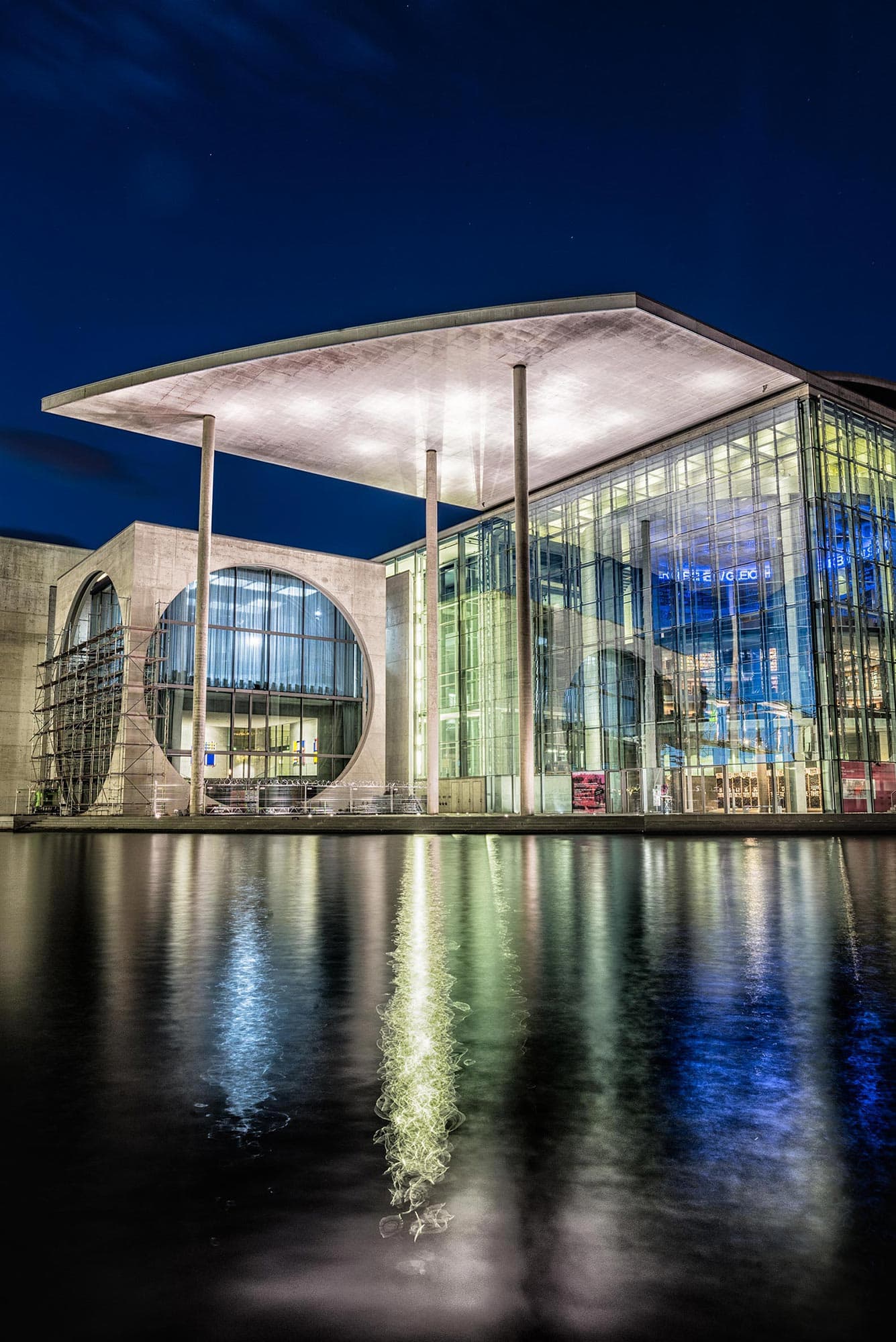 A large glass building is lit up at night.