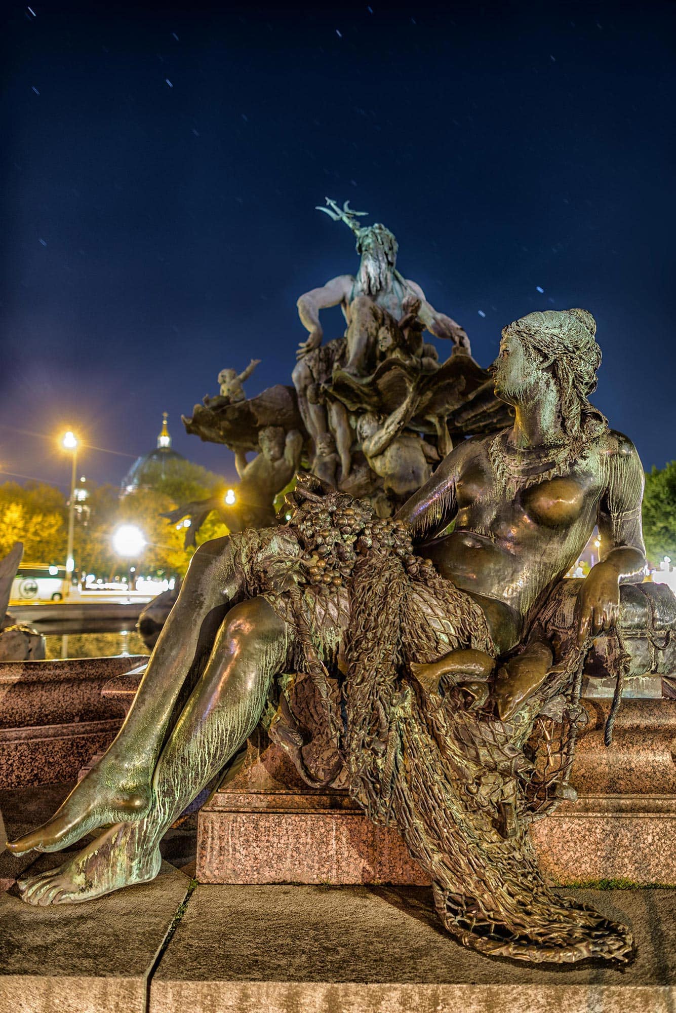 A statue of a woman laying on a bench at night.