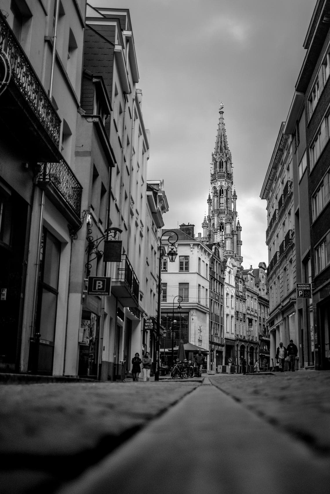 A black and white photo of a city street with a clock tower.