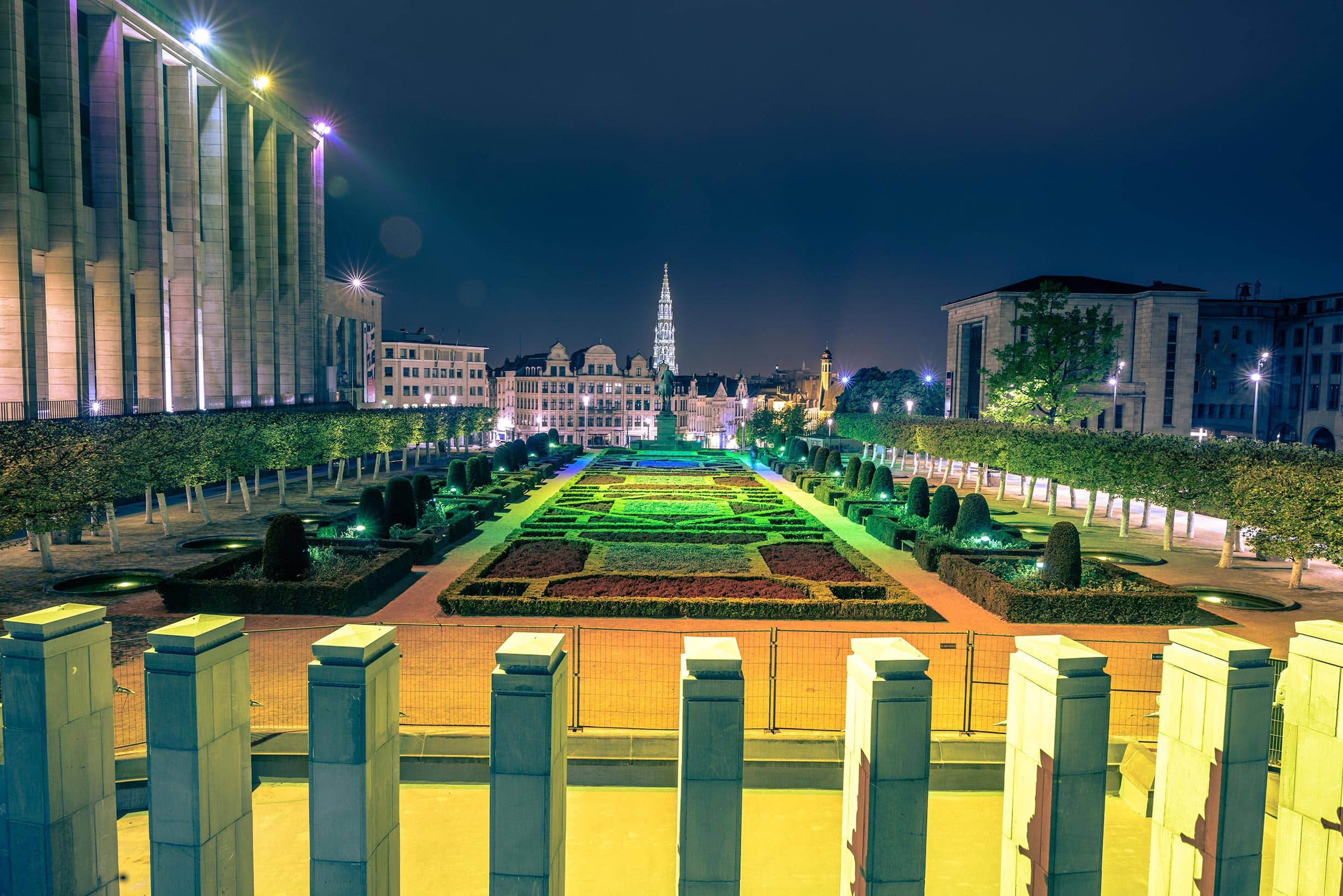 A view of a city at night with a garden in the background.