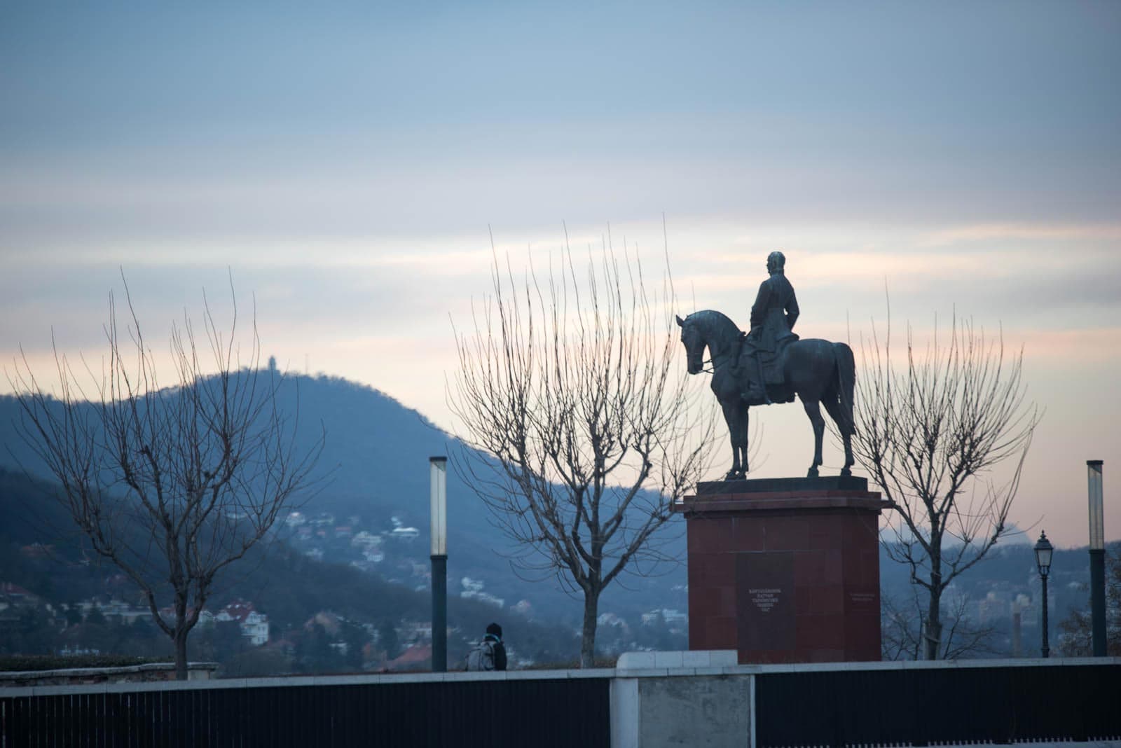 A statue of a man on a horse in front of a mountain.