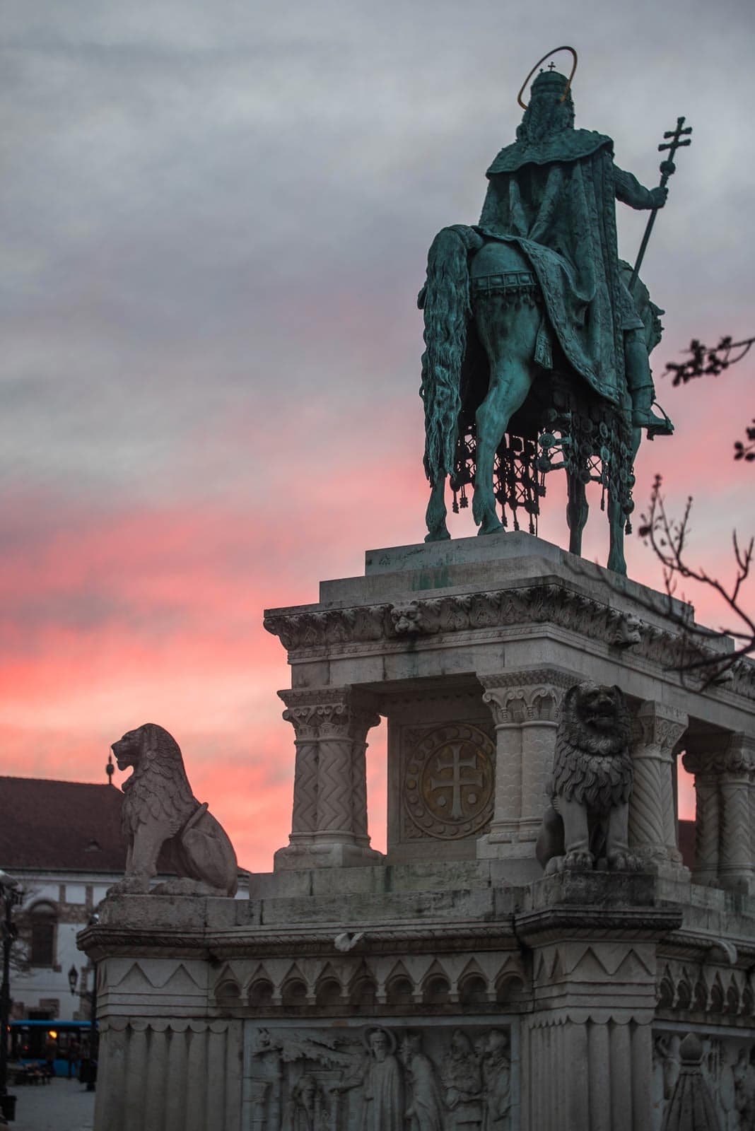 A statue of a man riding a horse in front of a sunset.