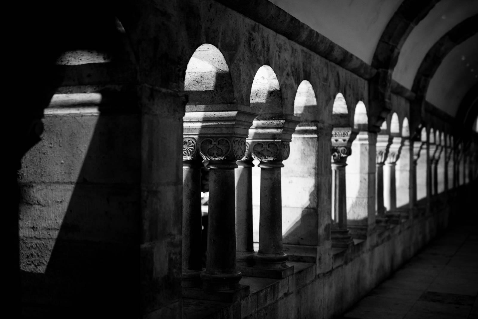 A black and white photo of arches in a hallway.