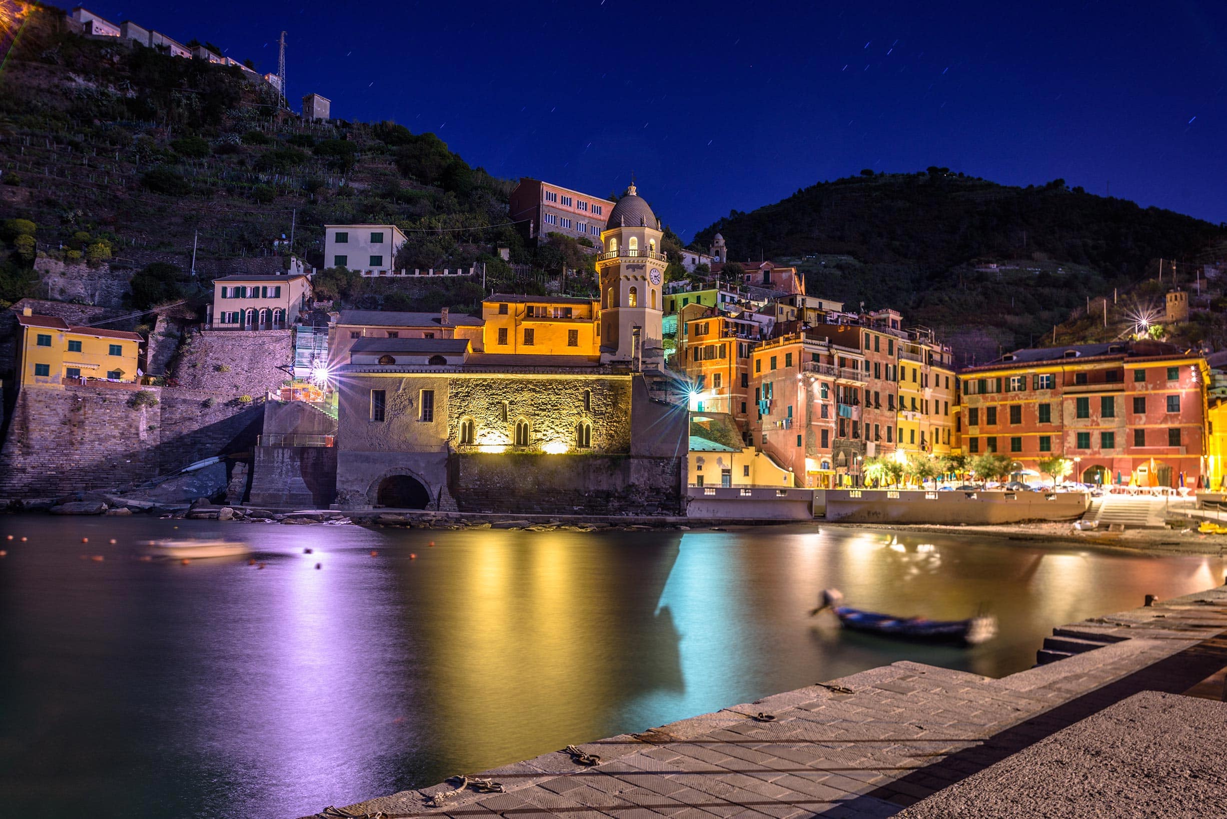 A town is lit up at night near a body of water.