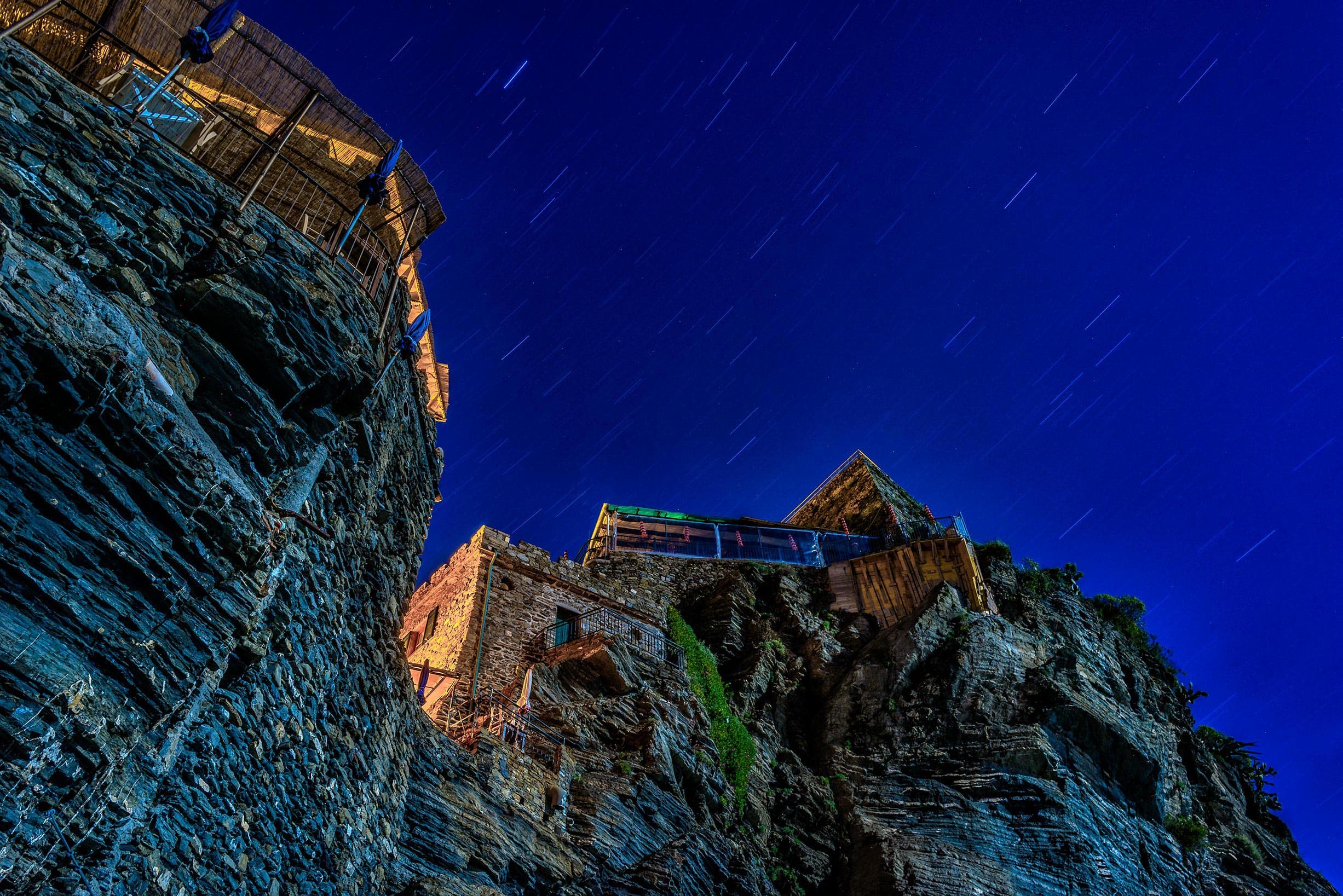 A building on a cliff at night with a starry sky.