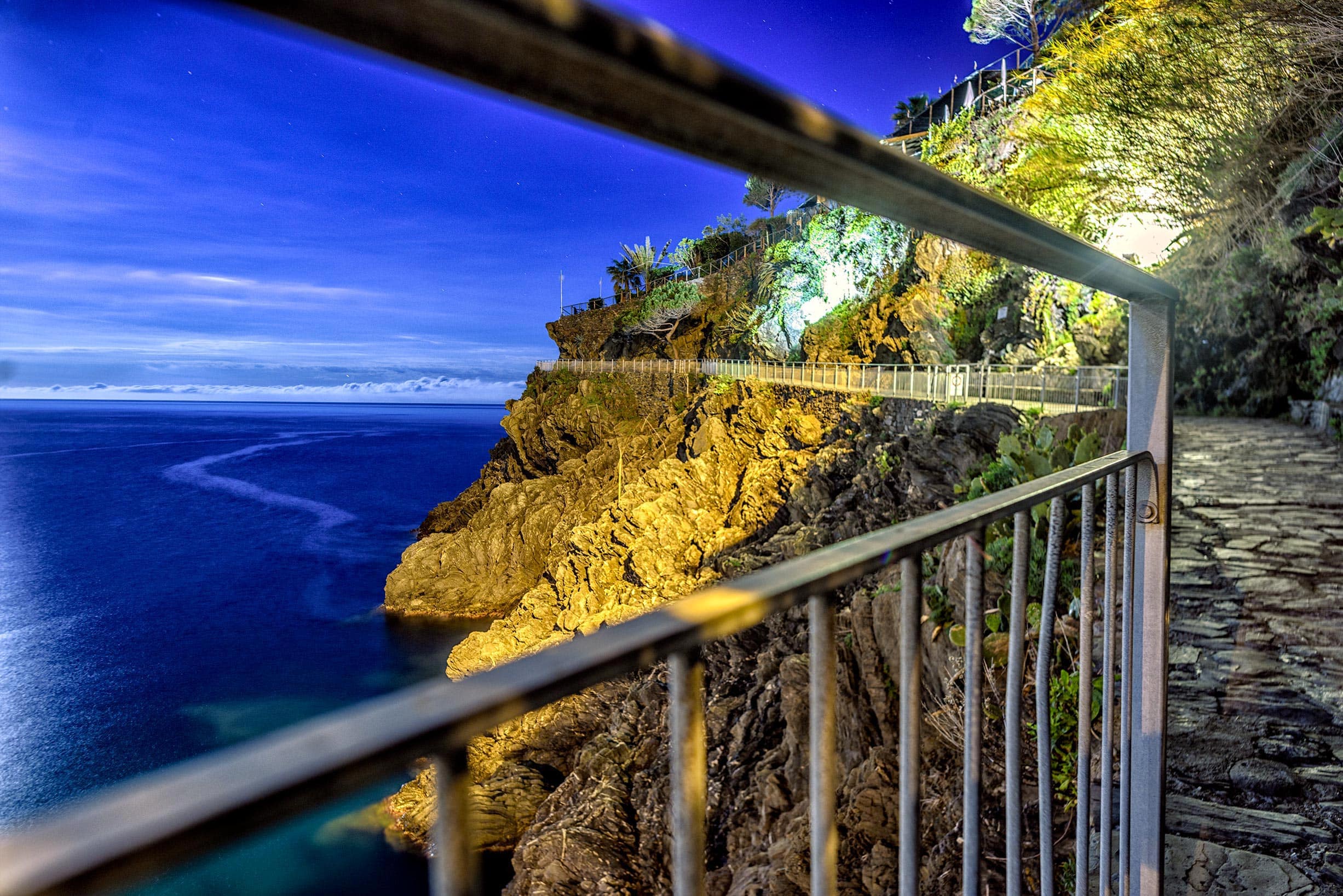 A view of the ocean from a railing at night.