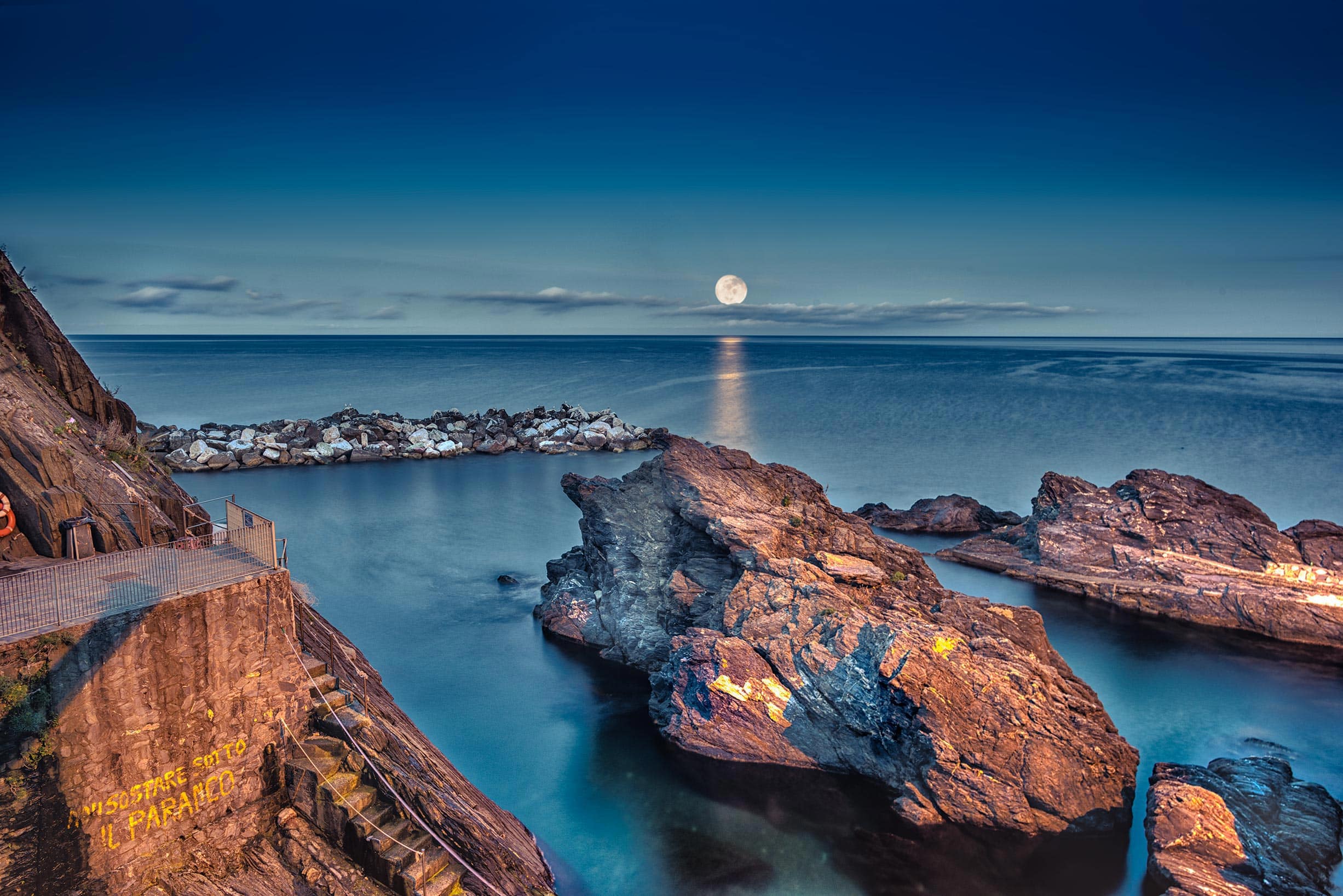 A full moon rising over a body of water.