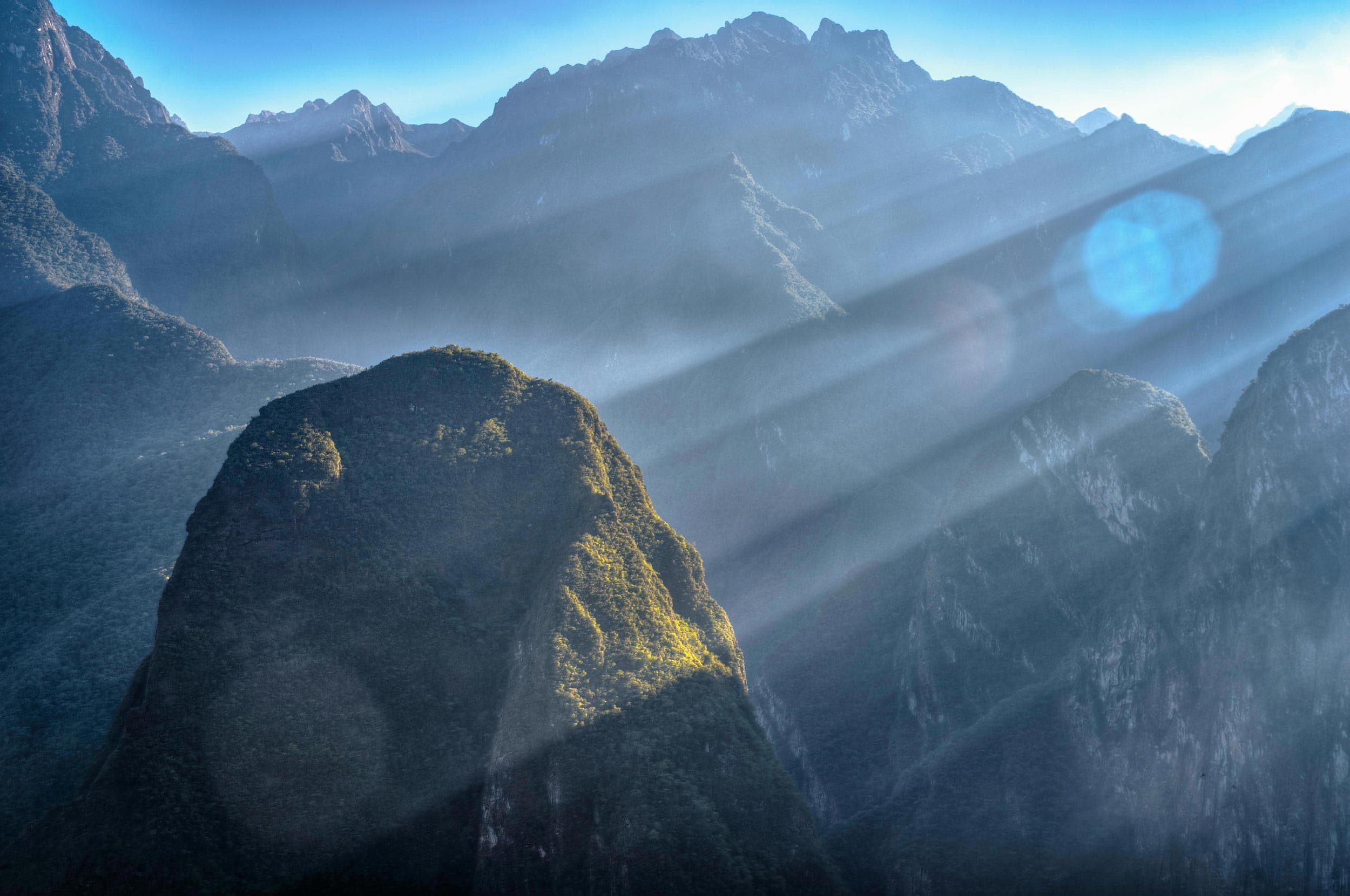 The sun rays are shining through a mountain range.