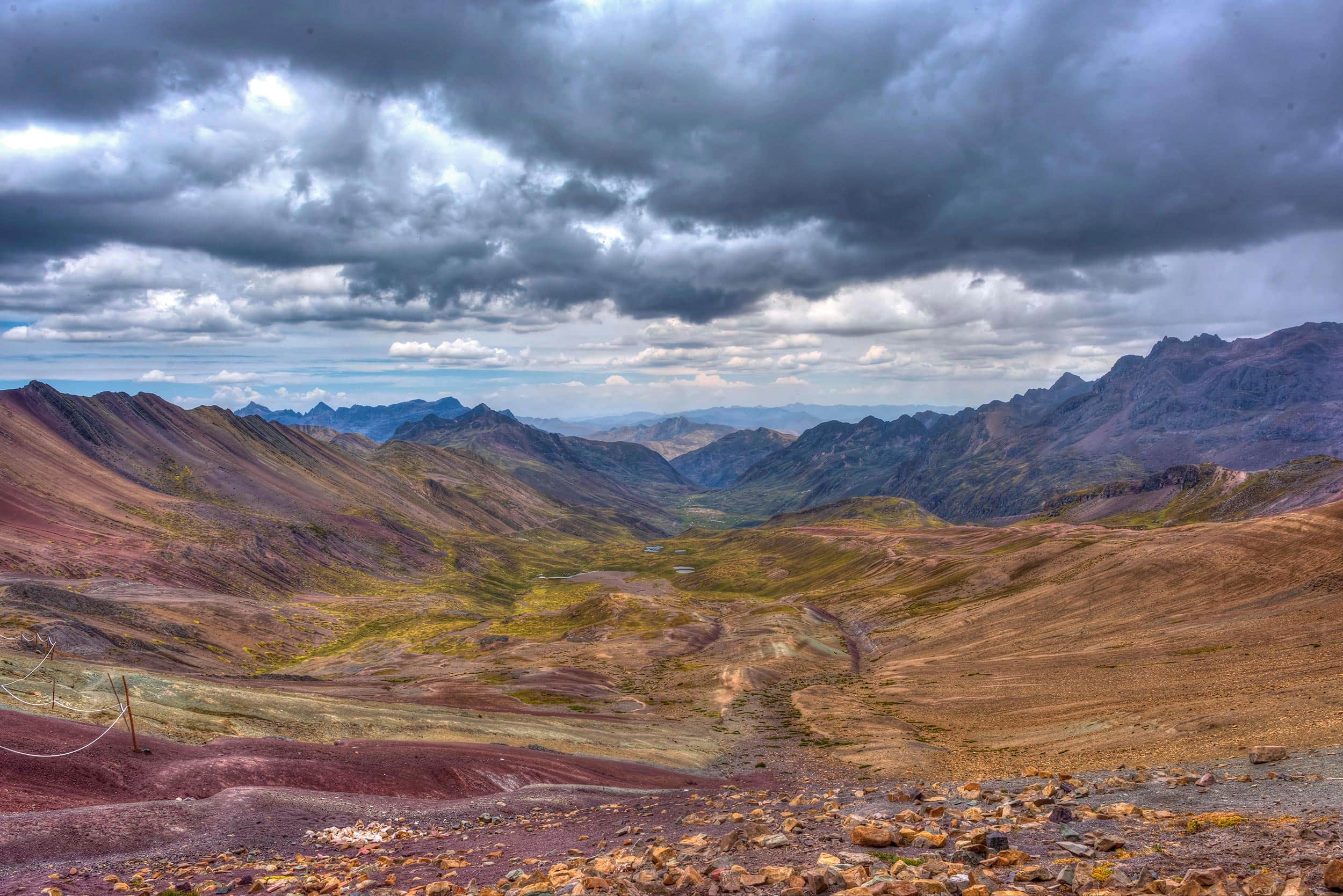 A view of a colorful valley under a stormy sky.