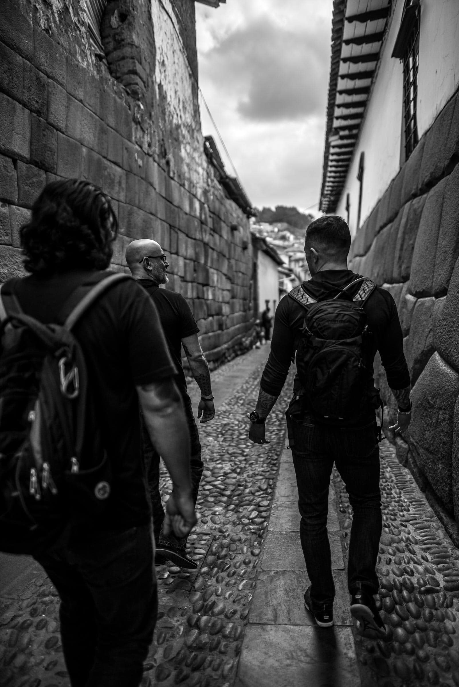 A group of people walking down a cobblestone street.