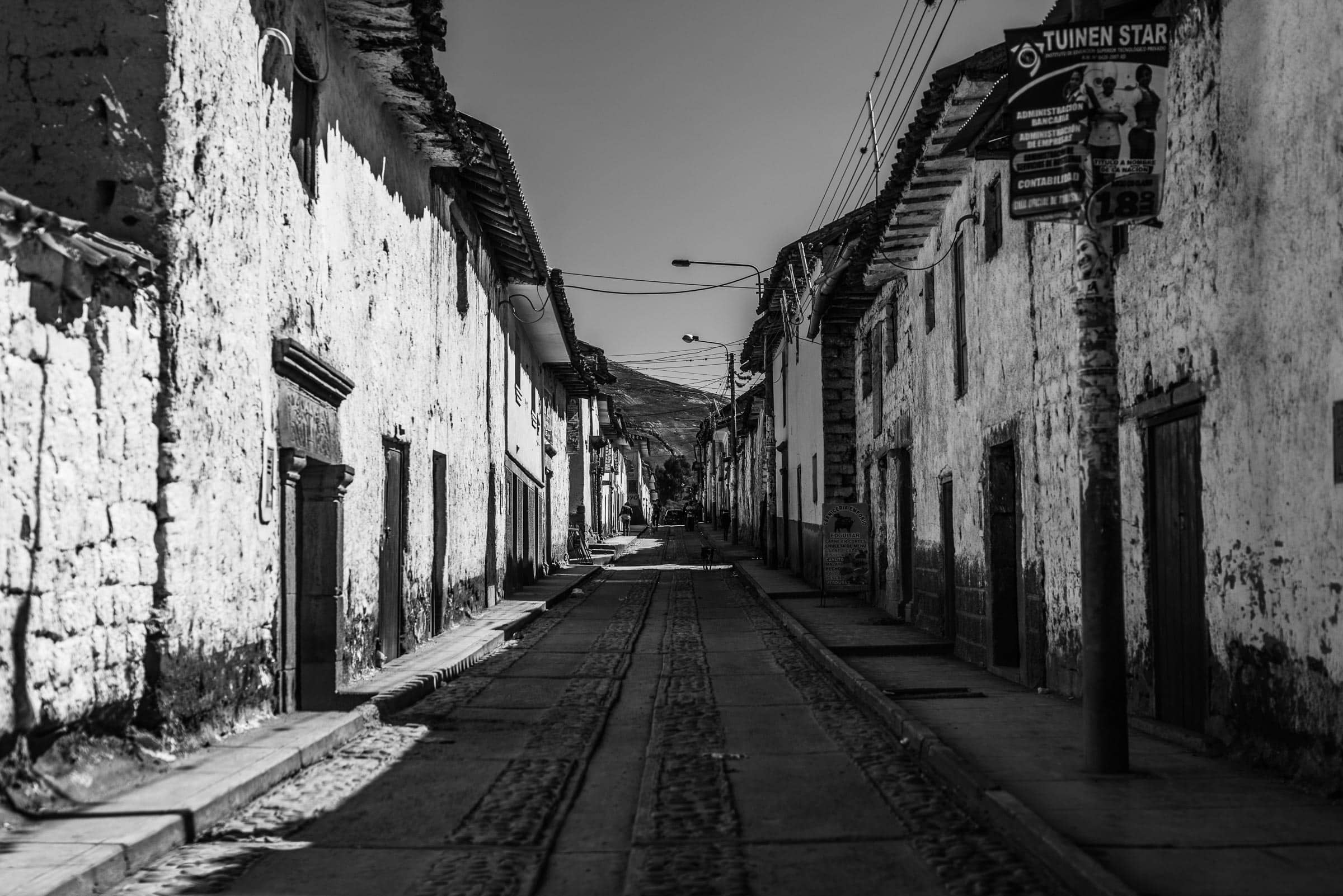 A black and white photo of a cobbled street in cusco.