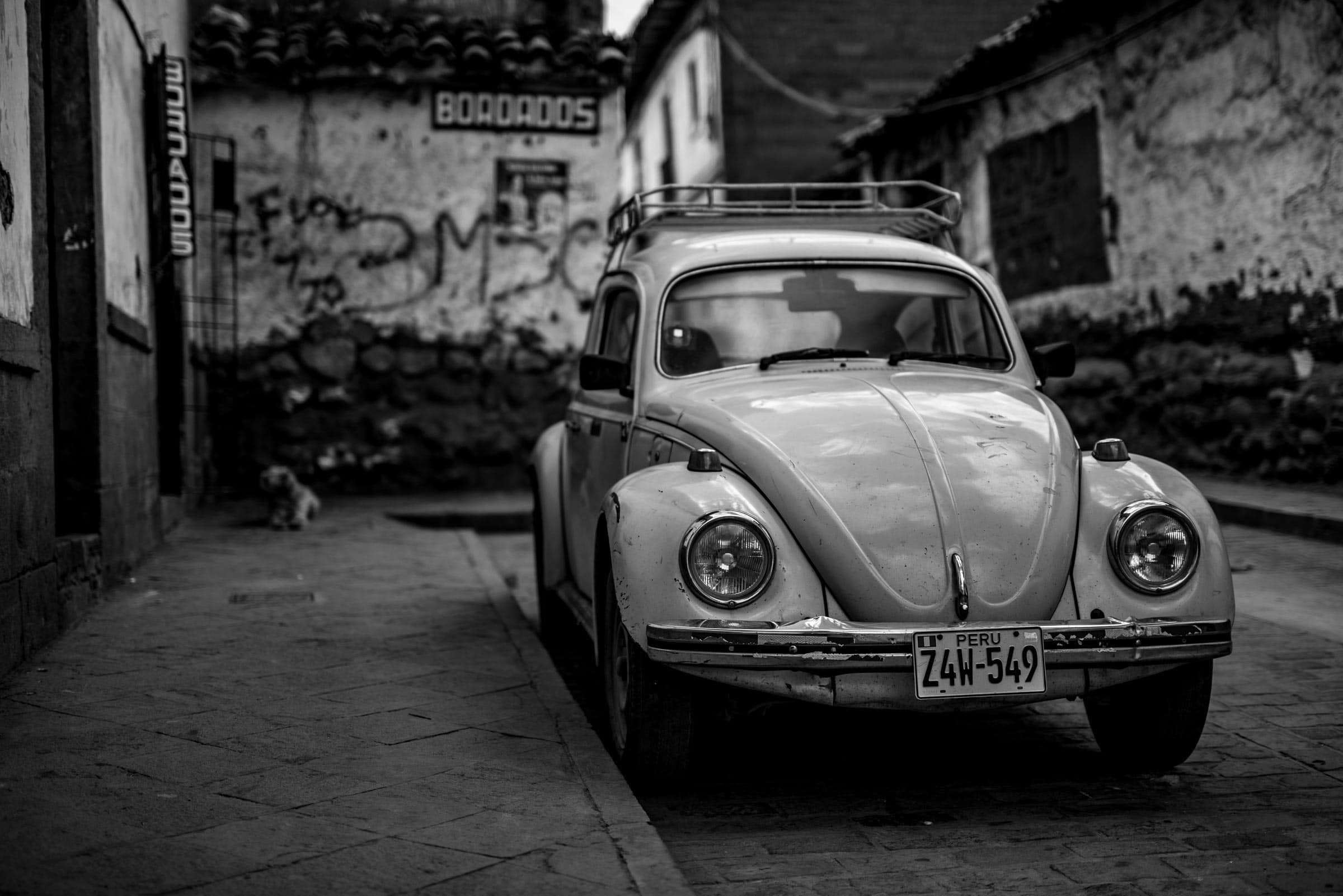 An old vw beetle parked on a street.