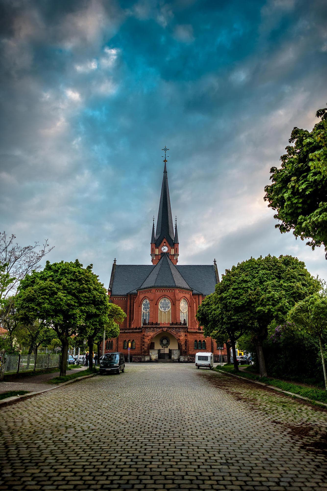 A church with a steeple in the middle of a cobblestone road.