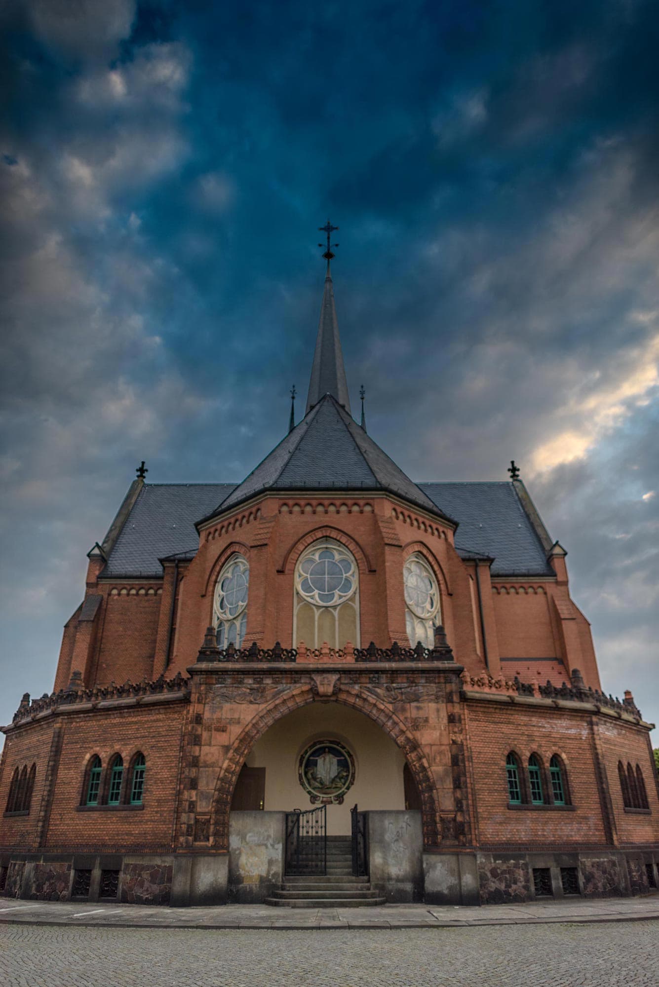 A church with a steeple under a cloudy sky.