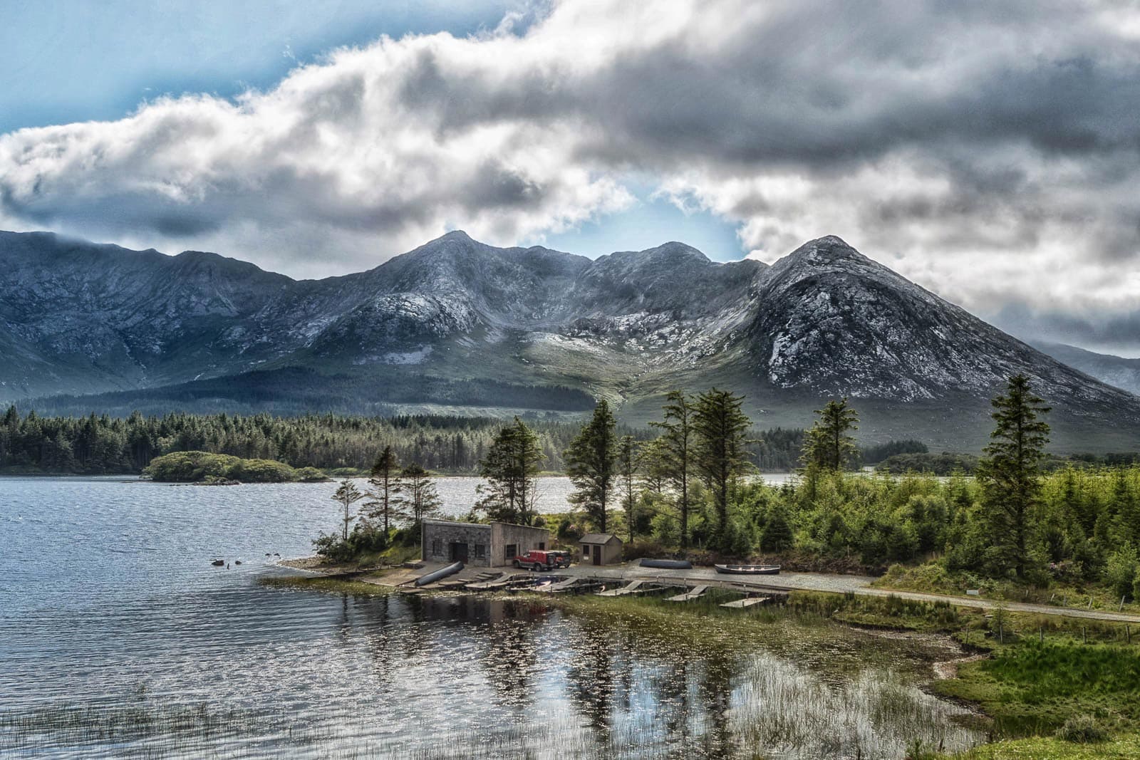 A lake surrounded by mountains under a cloudy sky.