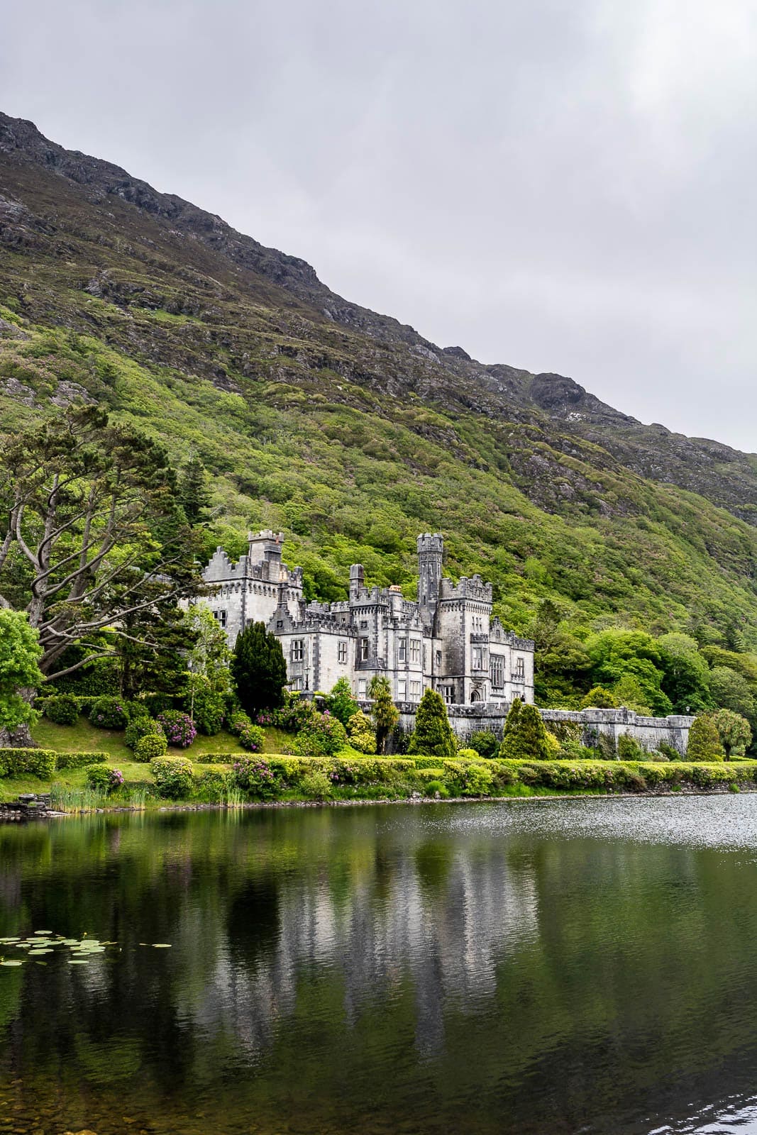 A castle sits on the edge of a lake in ireland.