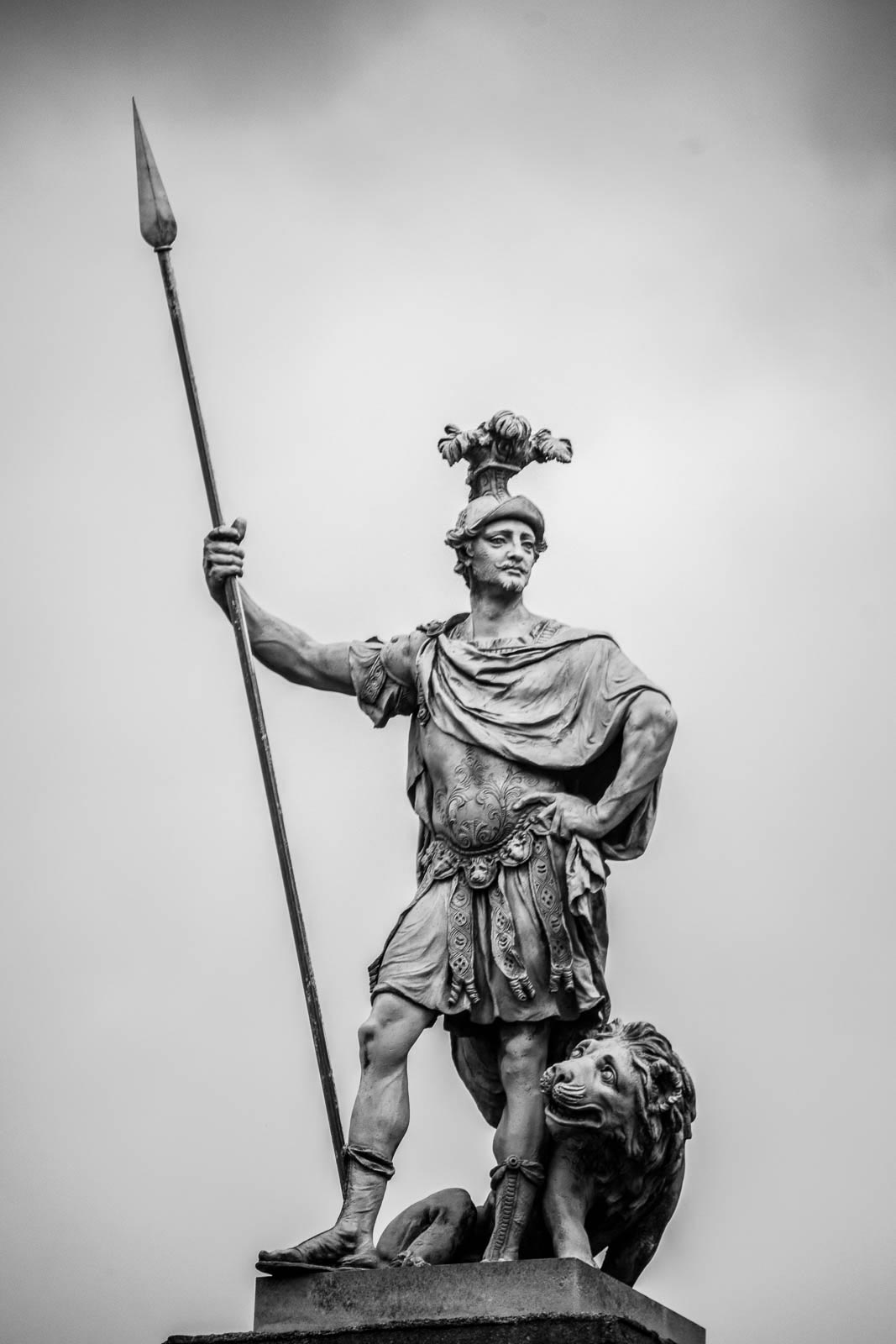 A statue of a man holding a spear and a lion.