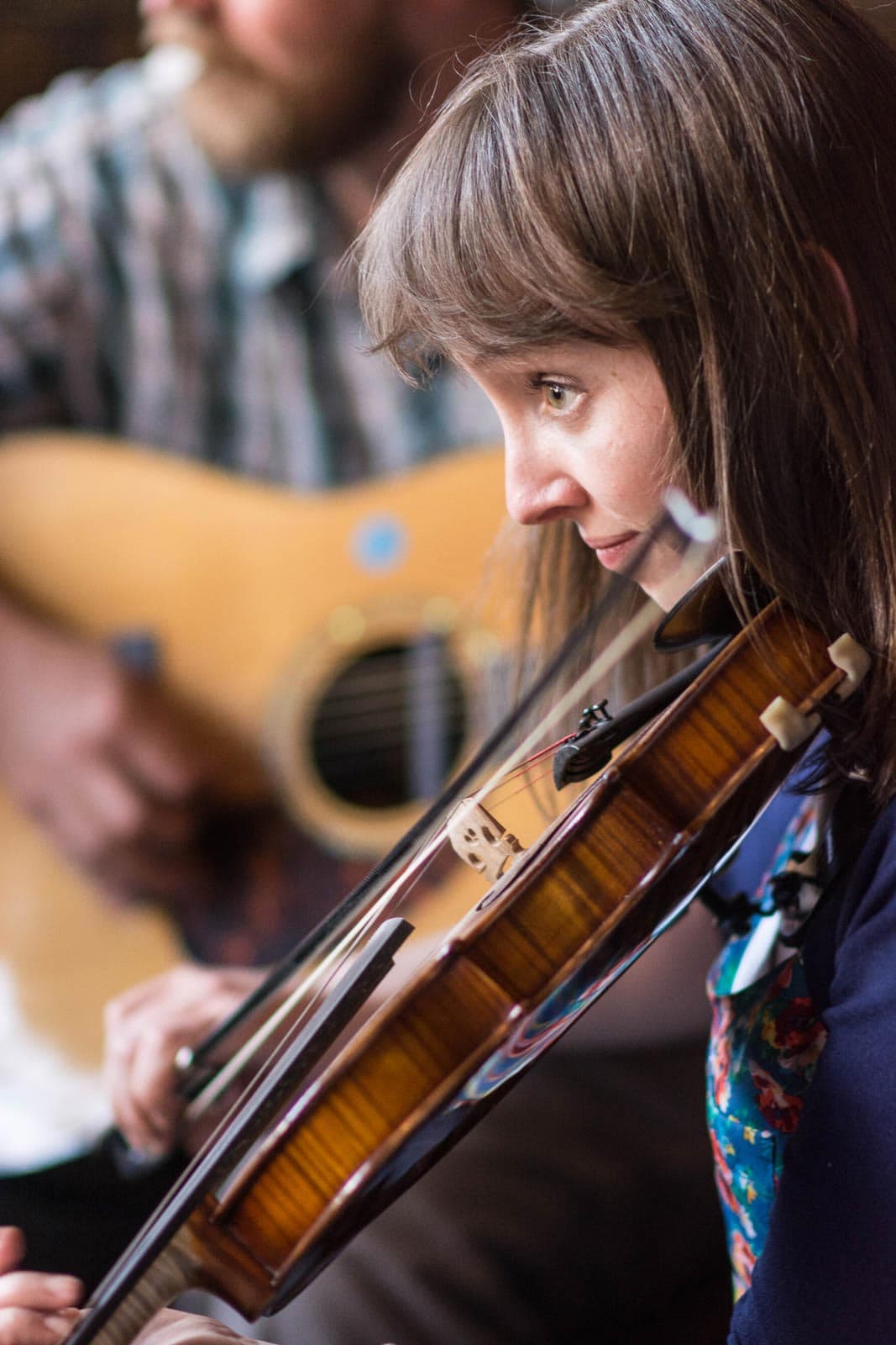 A woman playing a violin in front of a man.