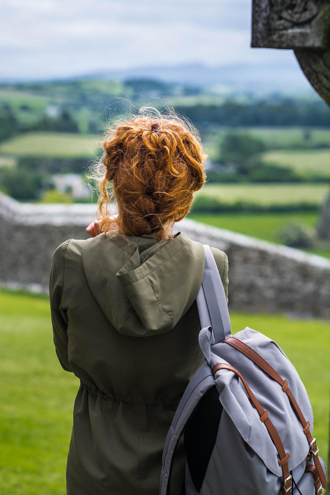 A woman with a backpack looking out over a field.