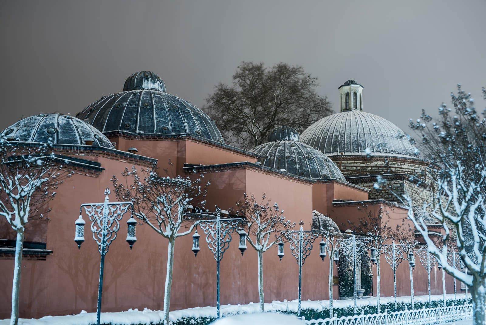 A snow covered building with domes in the background.