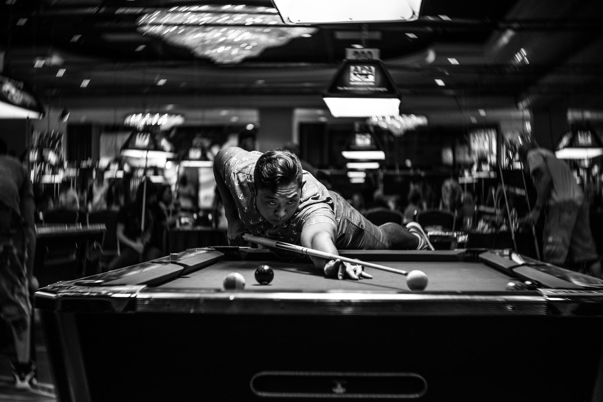 Black and white photo of a man playing billiards.