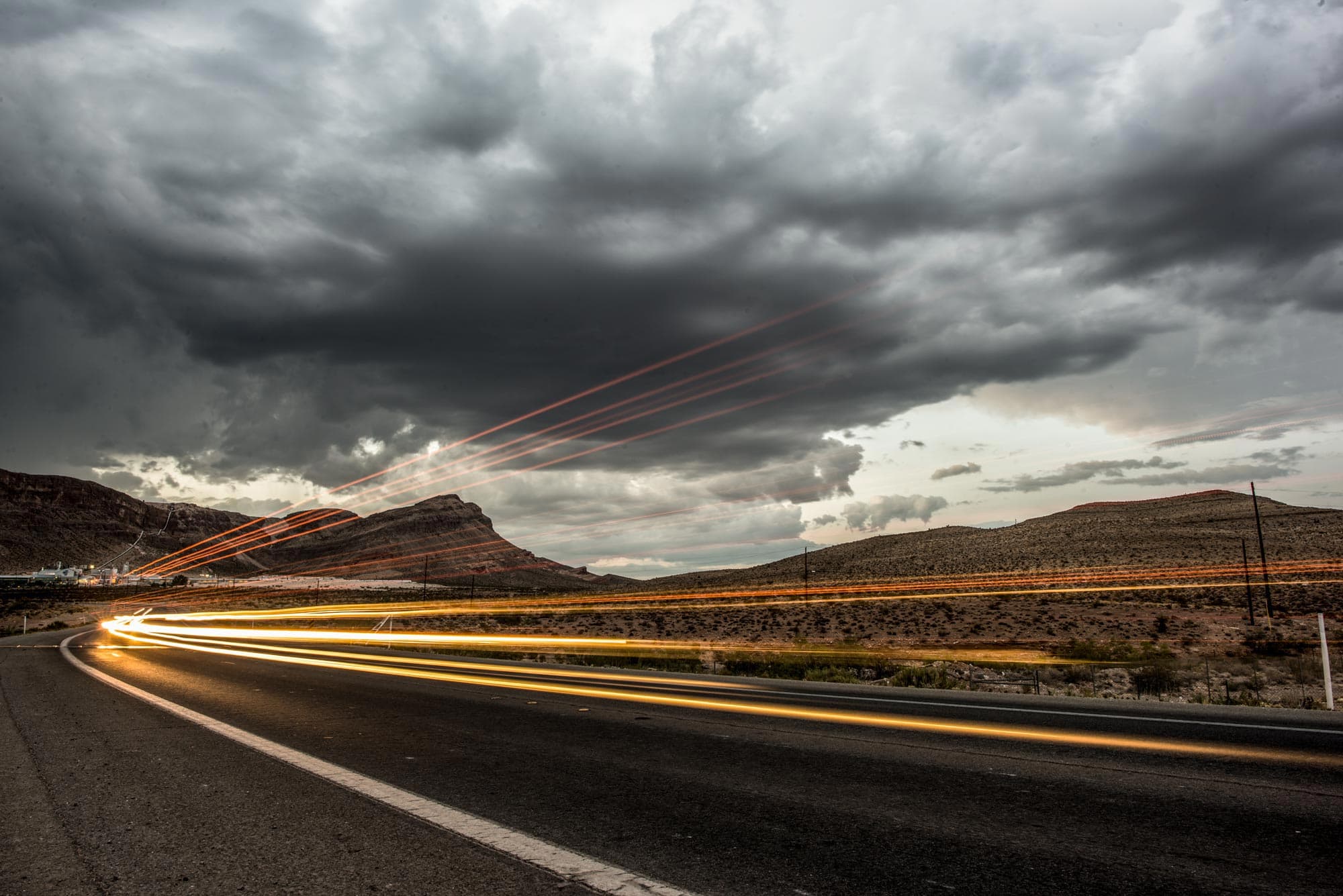 Light trails on a highway under a stormy sky.