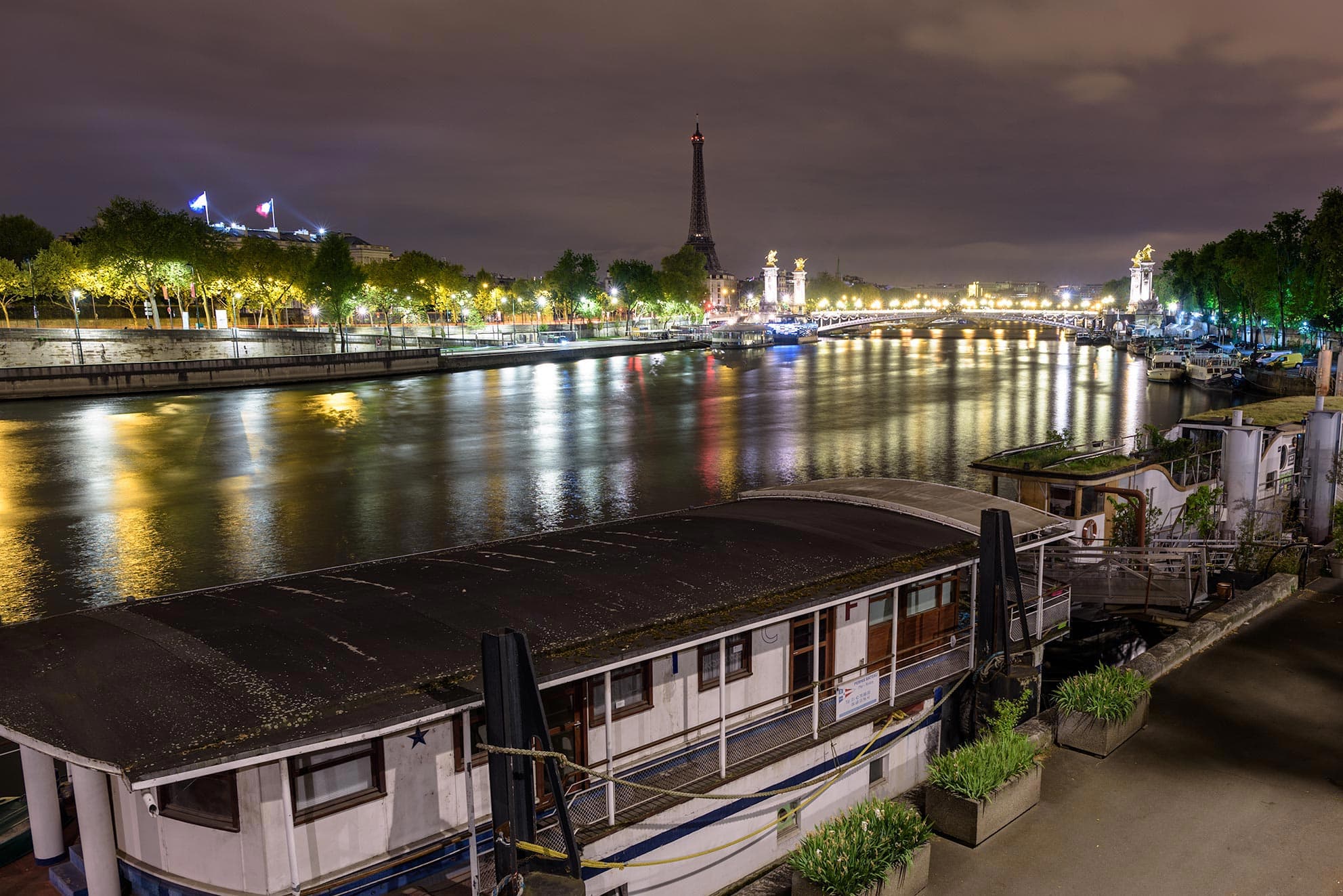 A boat docked on a river at night.