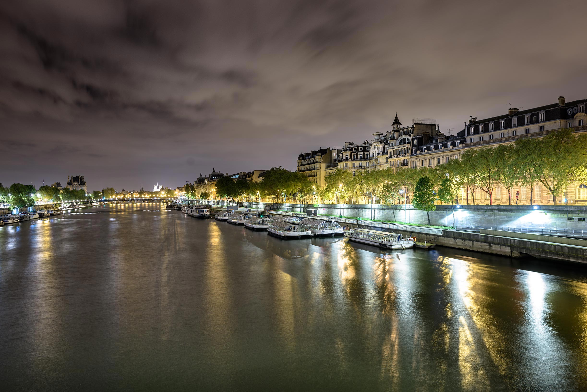 A river with boats docked in it at night.