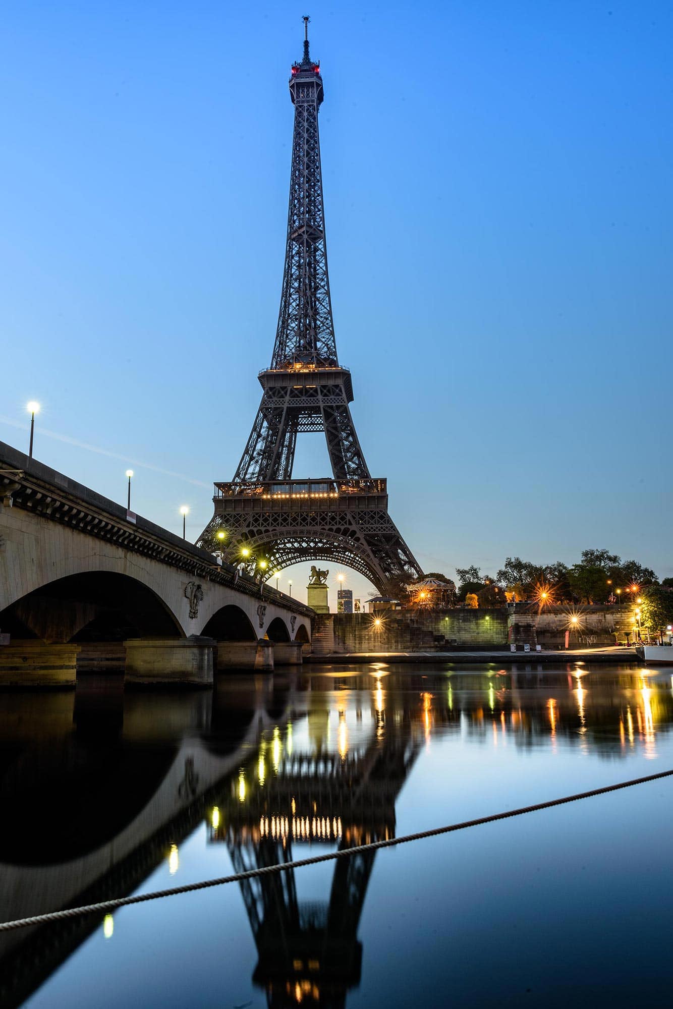 The eiffel tower is reflected in the water.