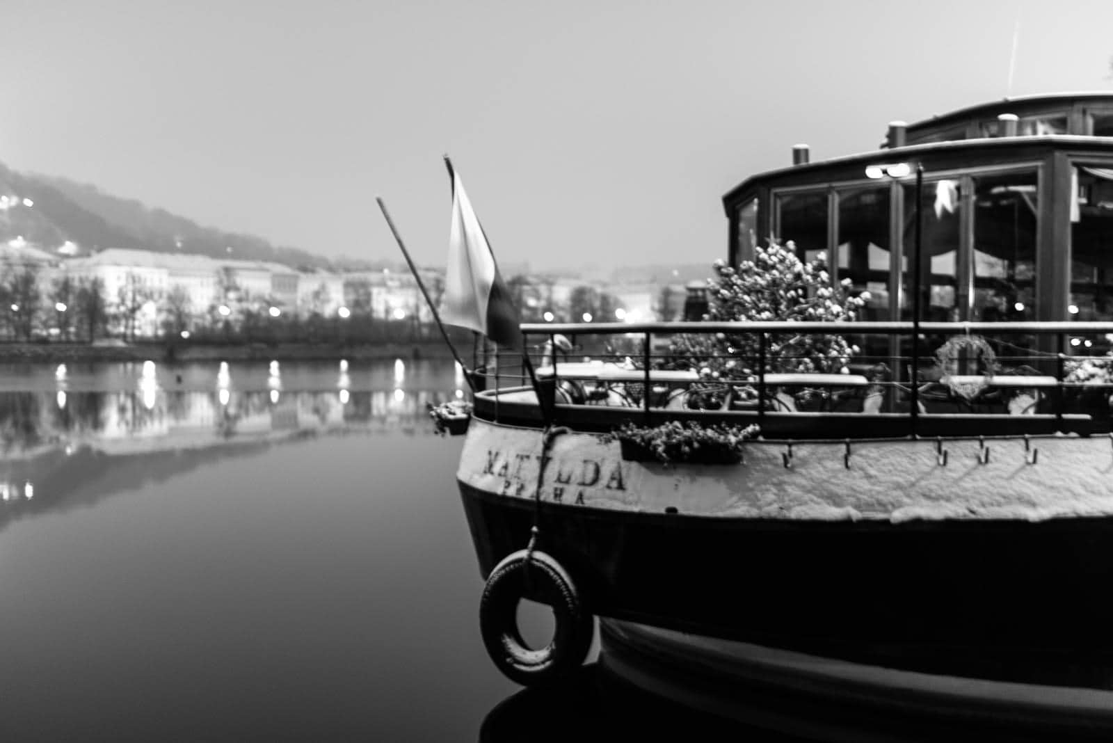 A black and white photo of a boat docked on a river.