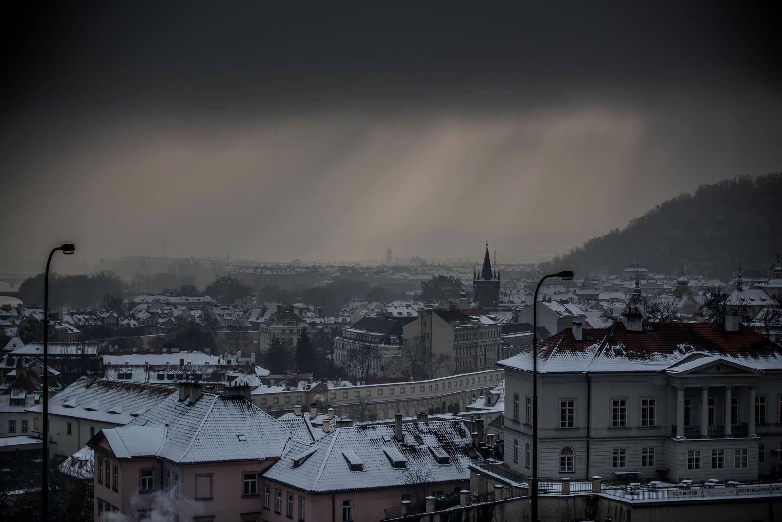 A city with snow covered buildings under a cloudy sky.