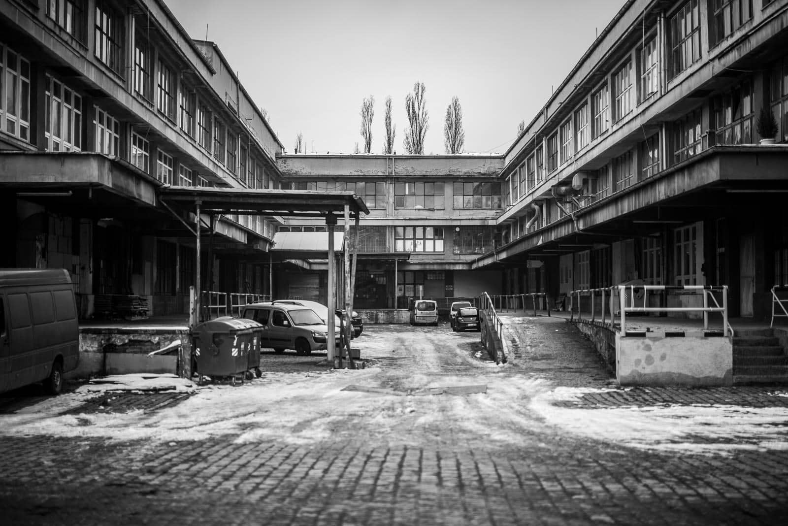 A black and white photo of a courtyard with cars parked in it.