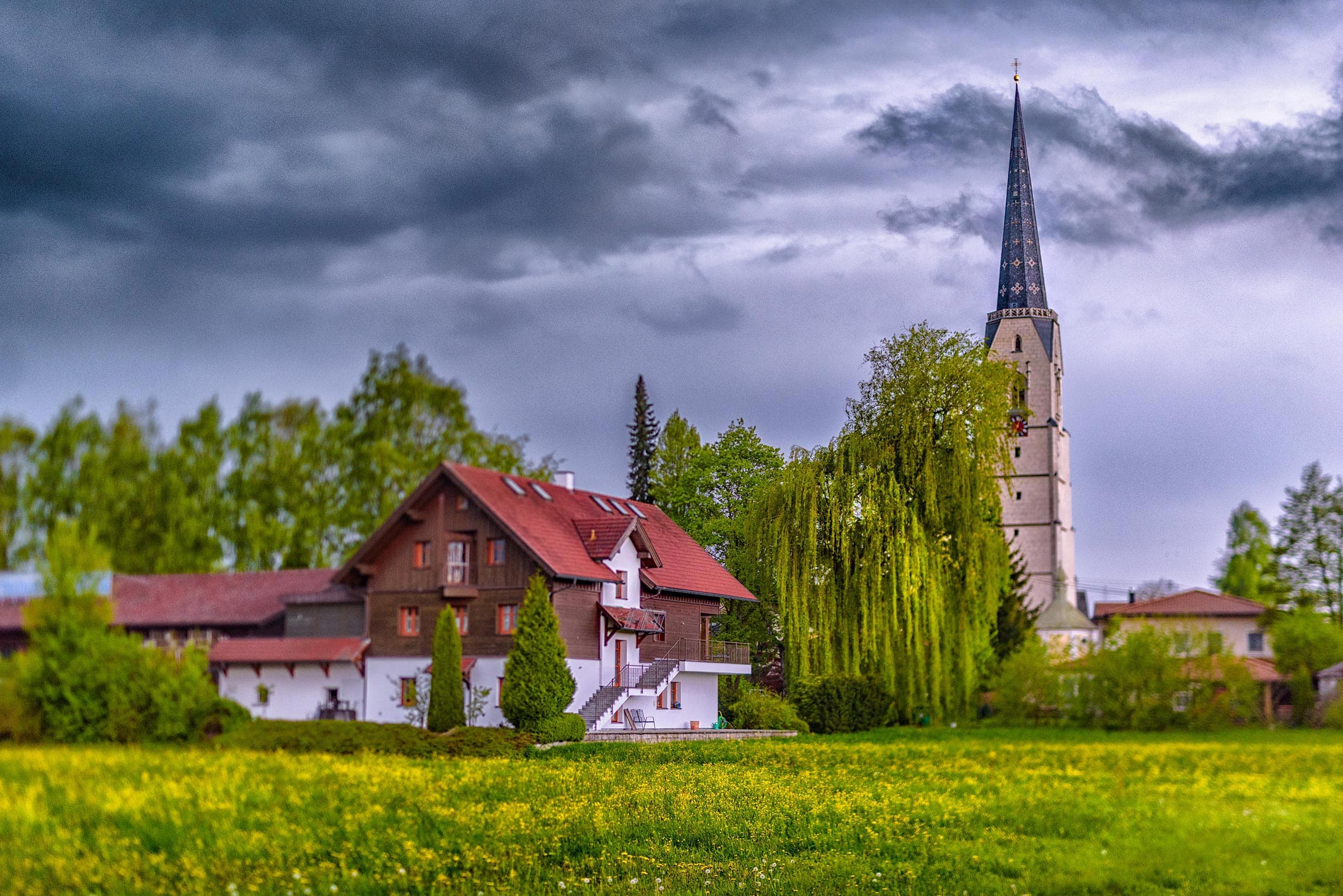 A church with a steeple in the middle of a field.