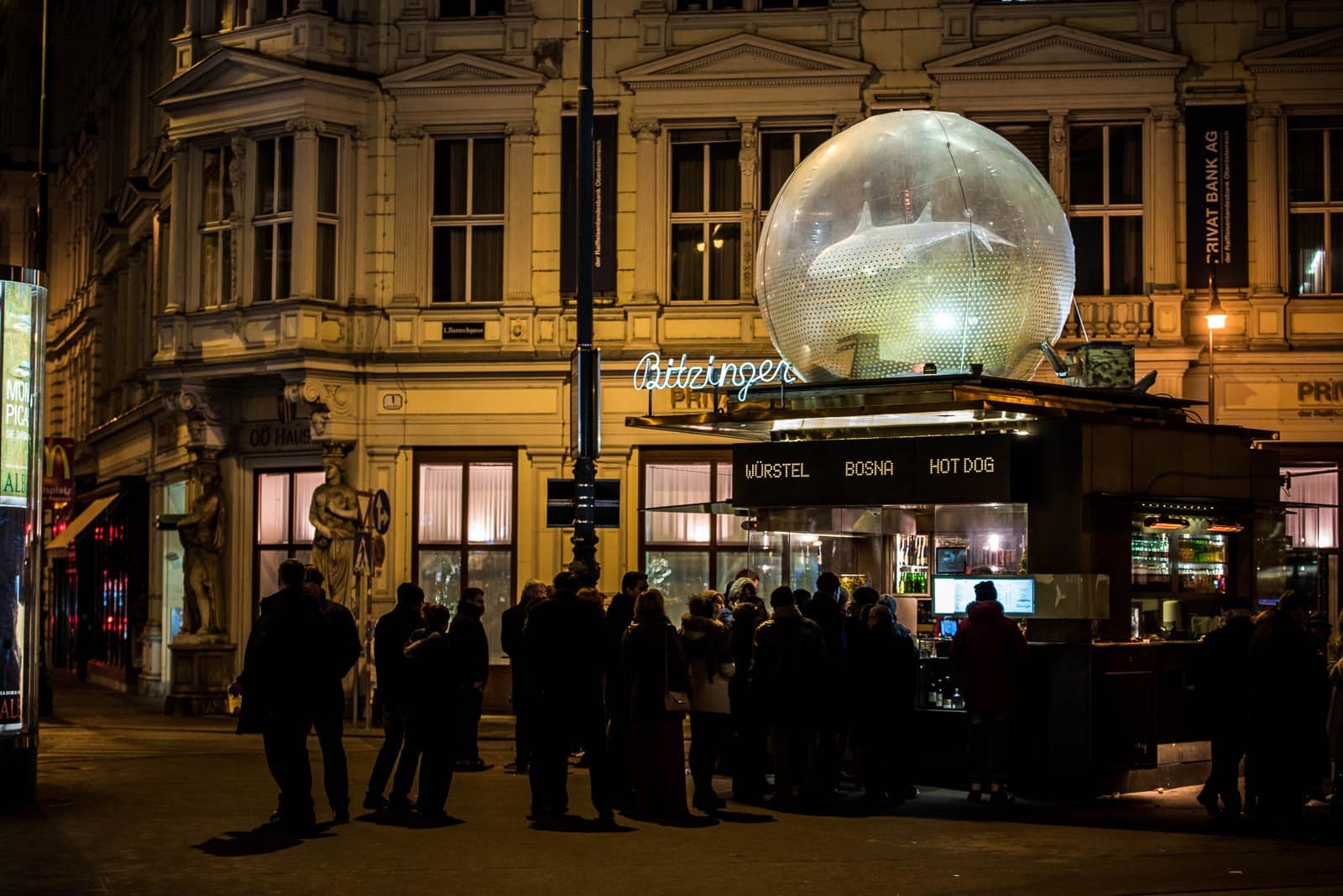 A group of people are standing in front of a large glass egg.