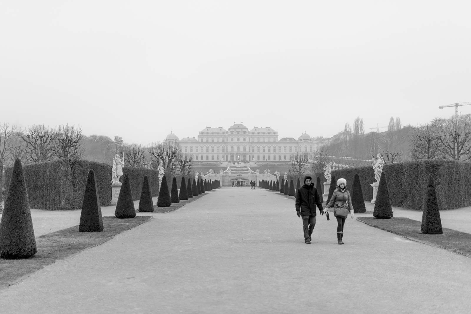 Two people walking down a path in front of a castle.