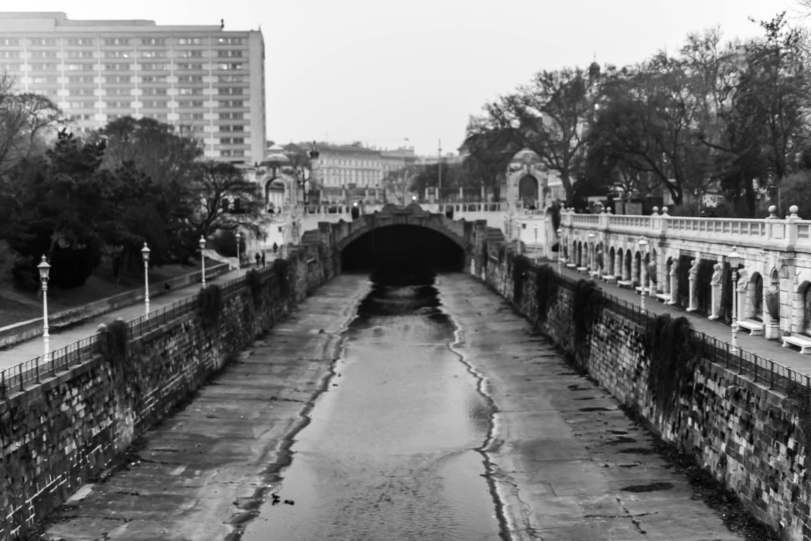 A black and white photo of a canal in a city.