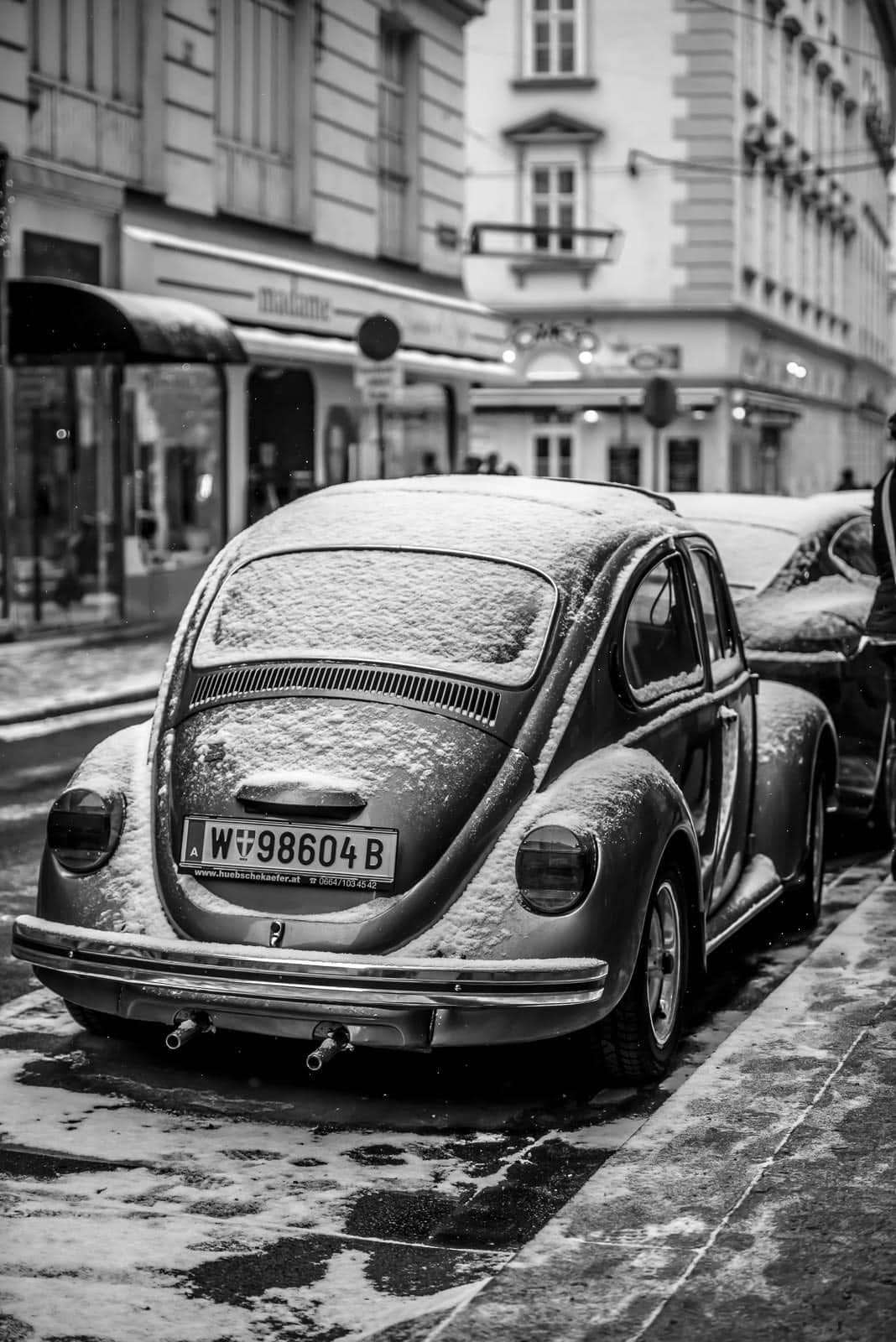 A black and white photo of a vw beetle parked on a street.