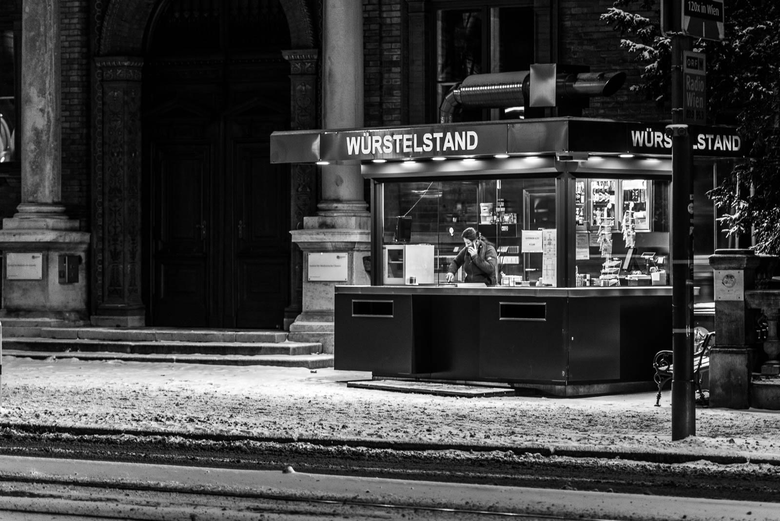 A black and white photo of a vending machine on a snowy street.