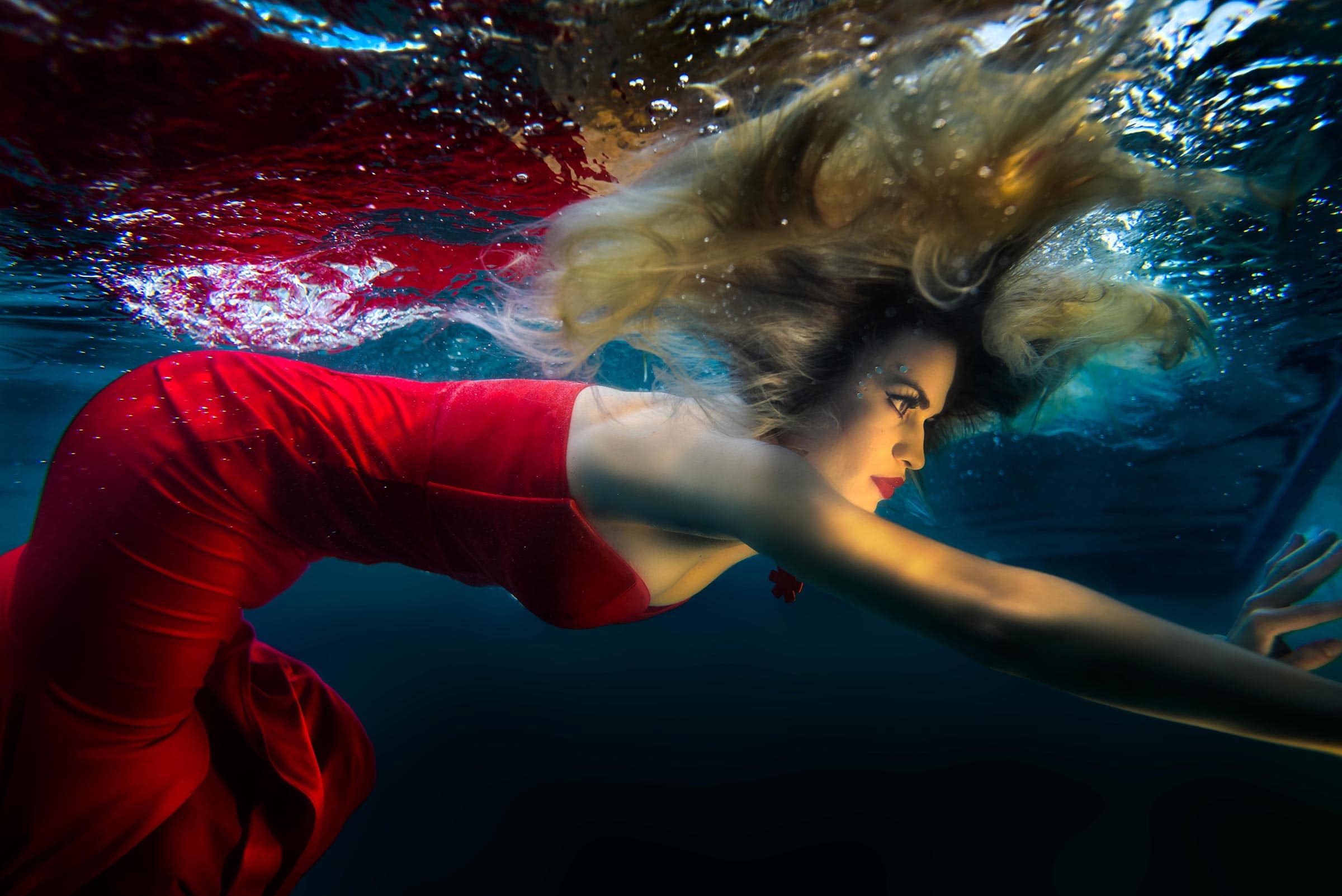 a mermaid in red looks into the light