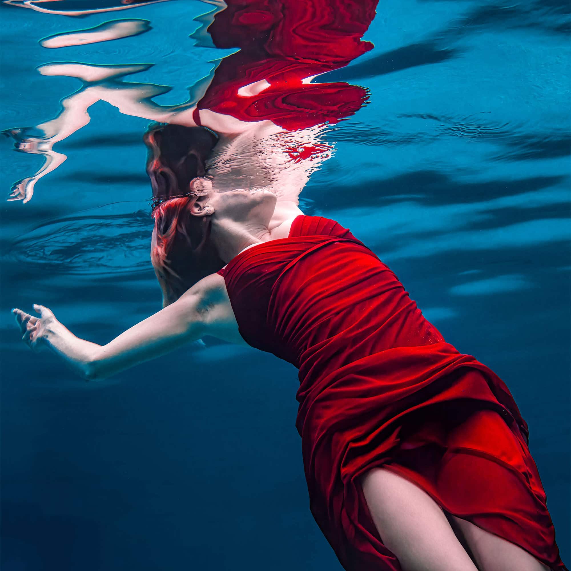 Houston photographer Chris Spicks captures the beauty of a woman in a red dress swimming underwater with his creative photography.