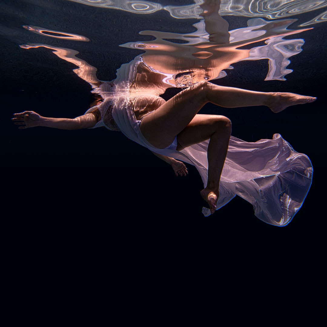 underwater maternity photoshoot woman's reflection in the murky waters