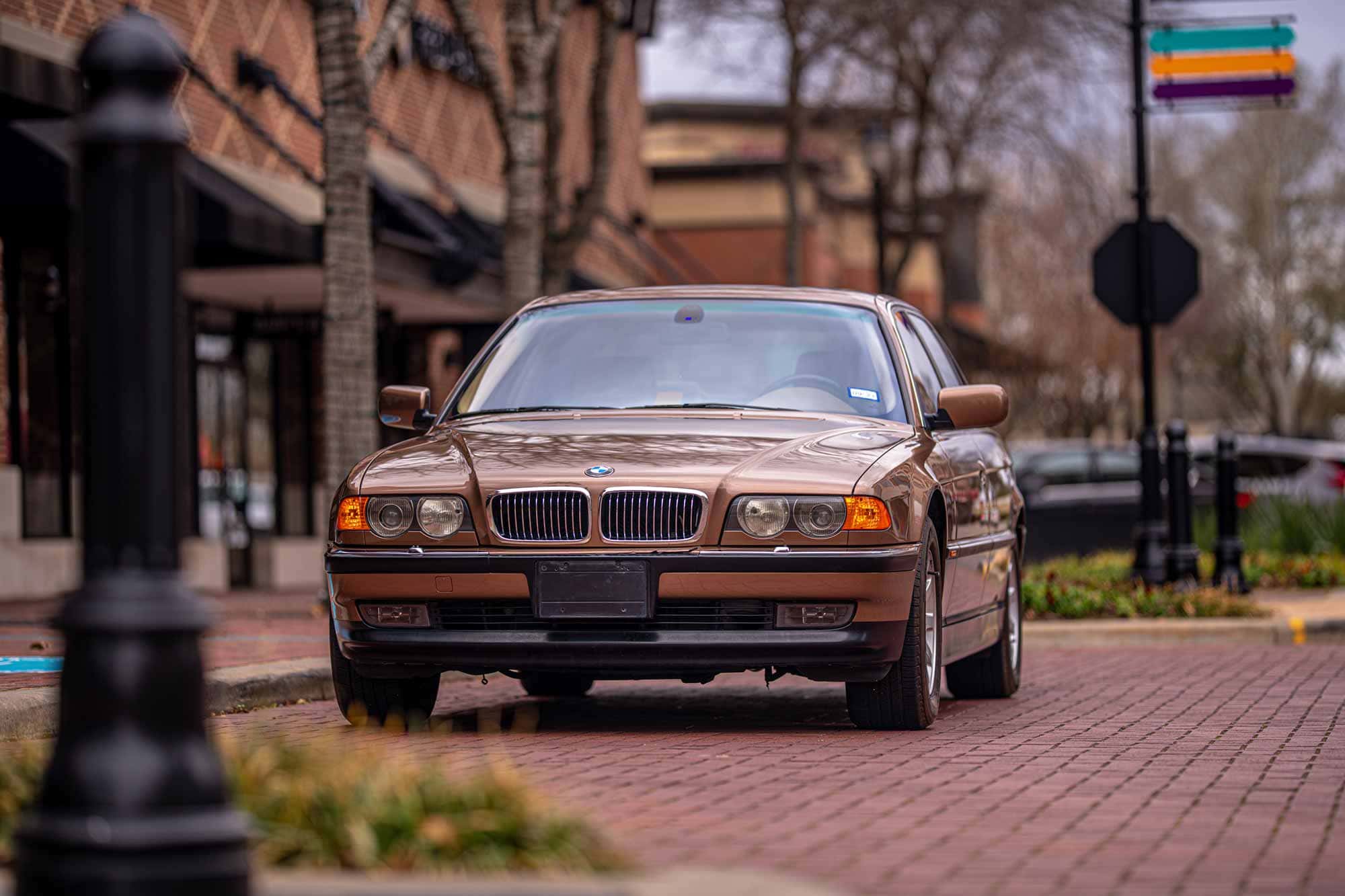 A creative photography by Chris Spicks Photography showcasing a brown BMW parked on a brick sidewalk in Houston.